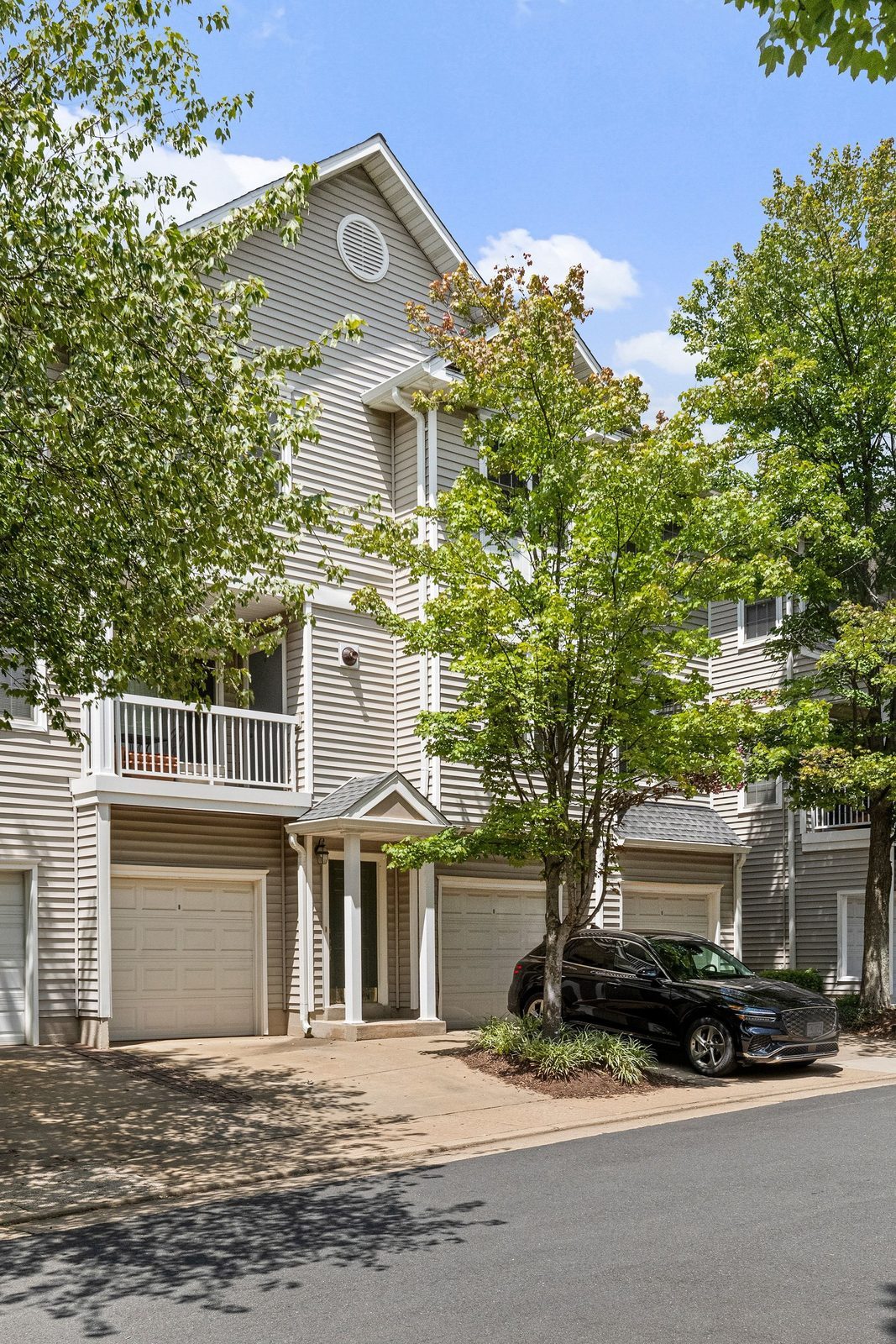 Three-story siding building with attached garages, covered entry and balcony