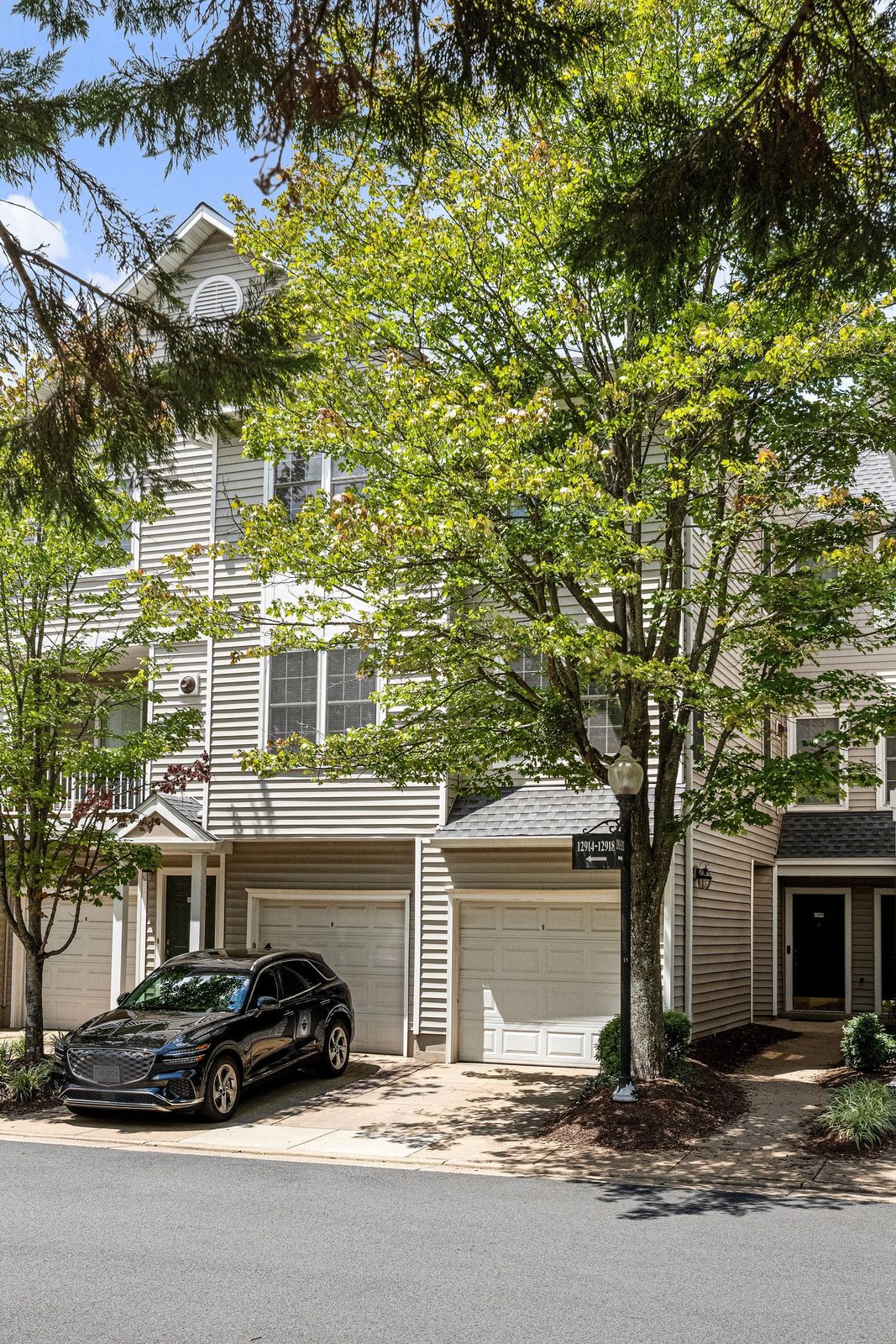 Siding building facade with two attached garage doors framed by trees