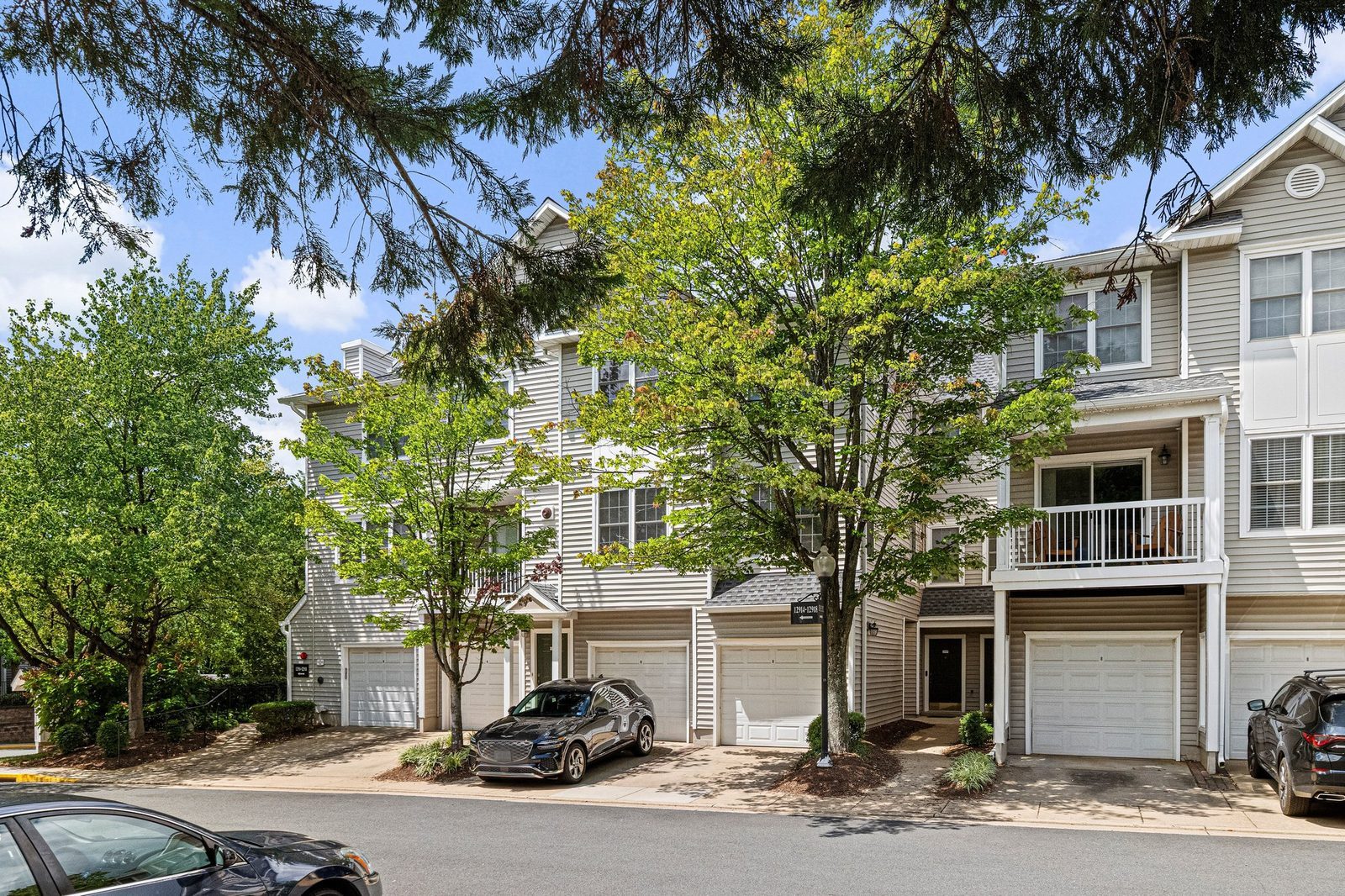 Street view of siding buildings with attached garages and second-floor balcony