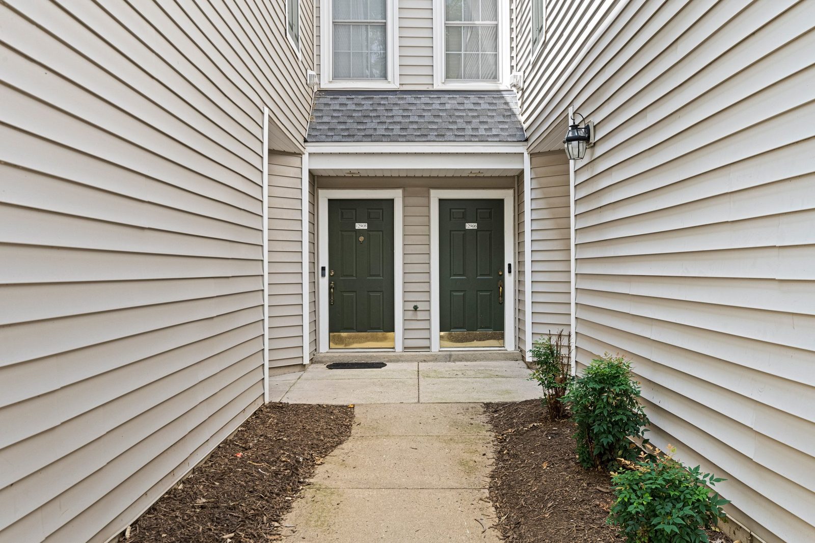 Recessed entry alcove with two dark green paneled front doors, unit 12908