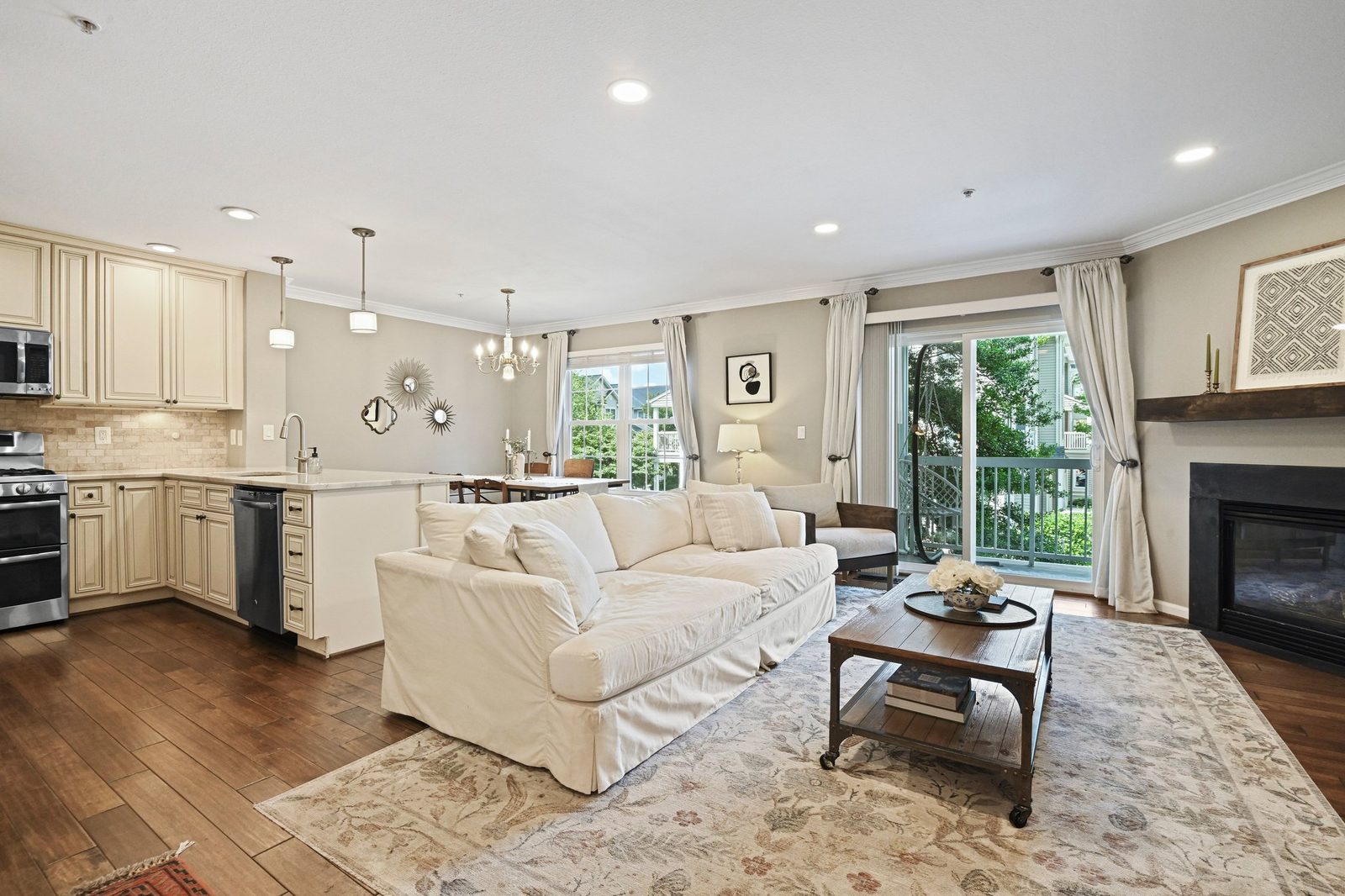 Open living area with hardwood floors, kitchen peninsula, fireplace and balcony doors