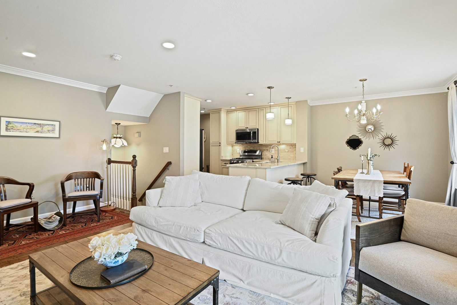Living and dining area with white sofa, chandelier and open kitchen beyond