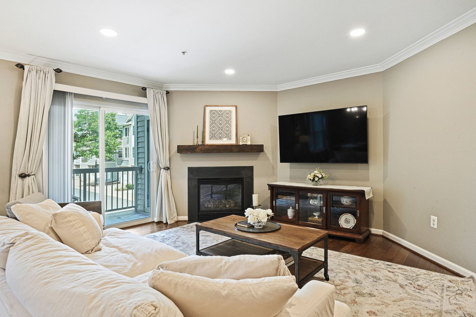 Living room with gas fireplace, wood mantel and sliding balcony doors