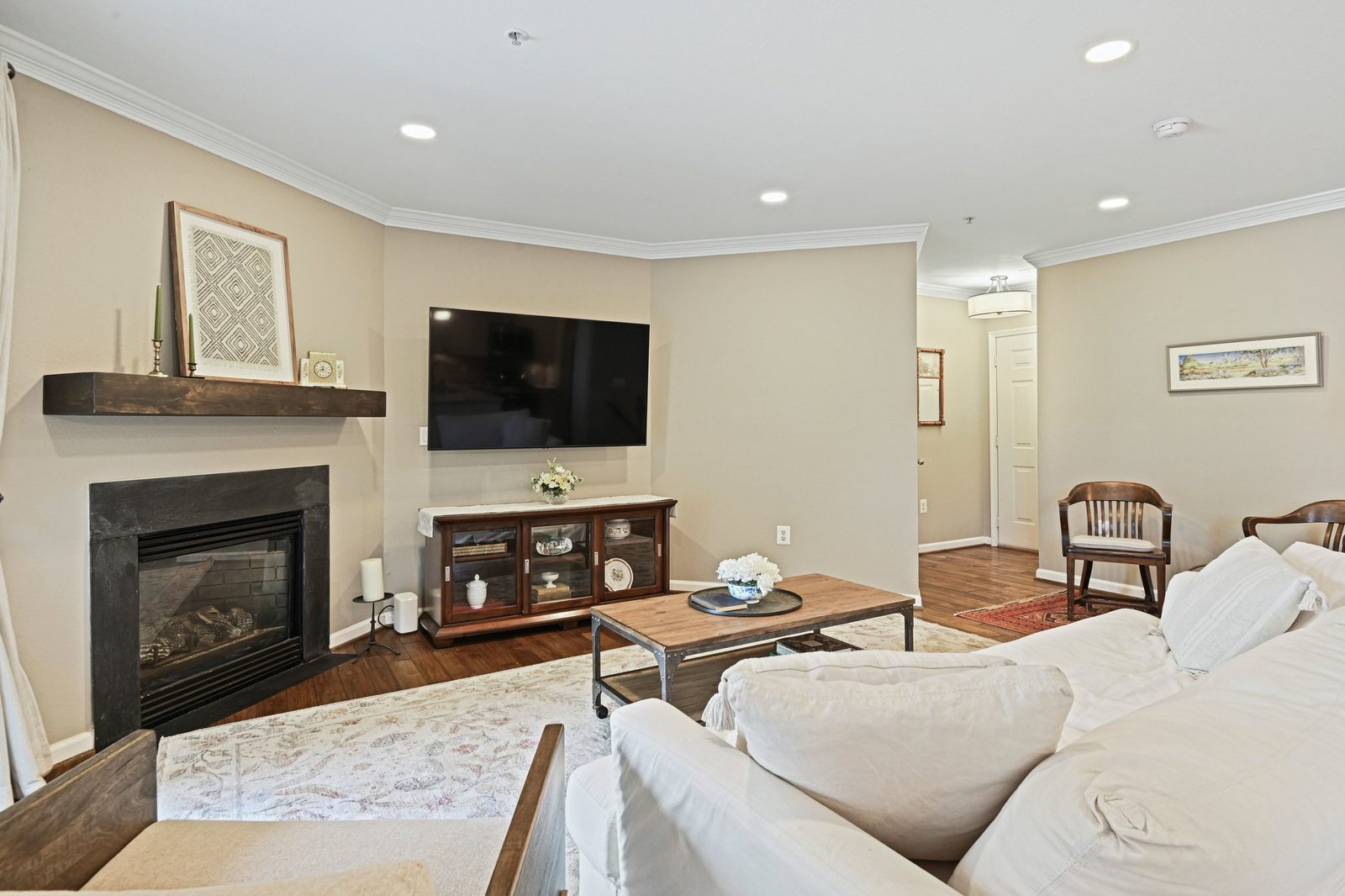 Living room with gas fireplace, wood mantel, hardwood floors, mounted TV