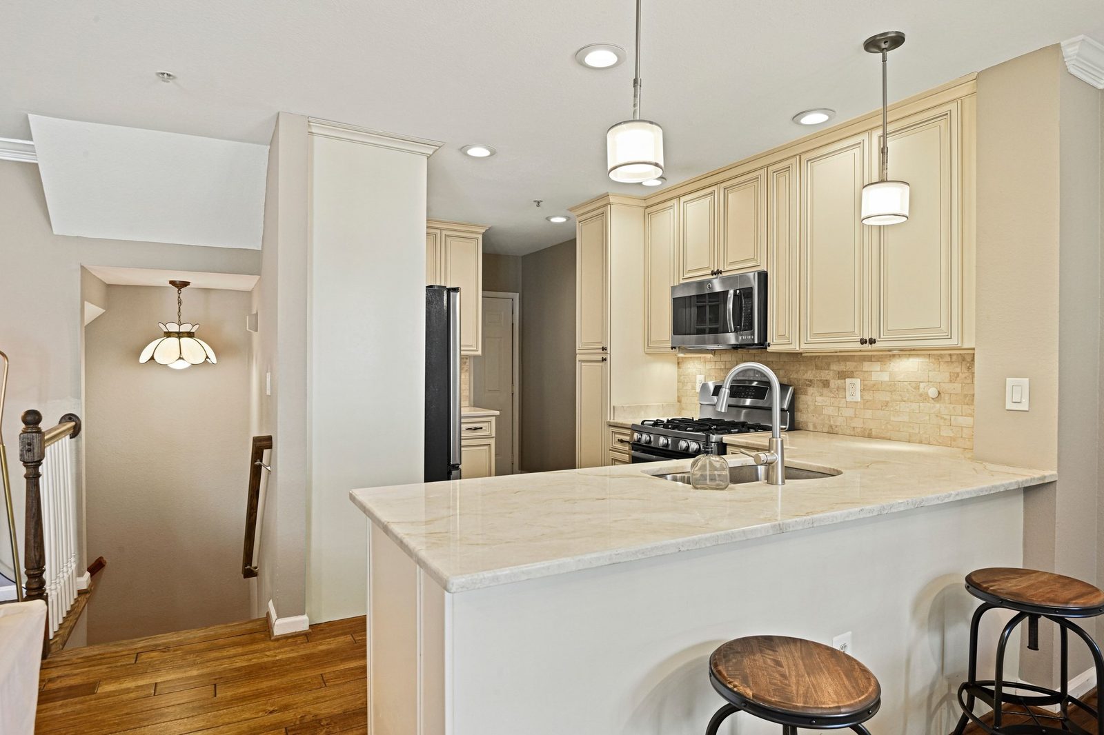 Kitchen peninsula with counter seating, pendant lights, and hardwood floors