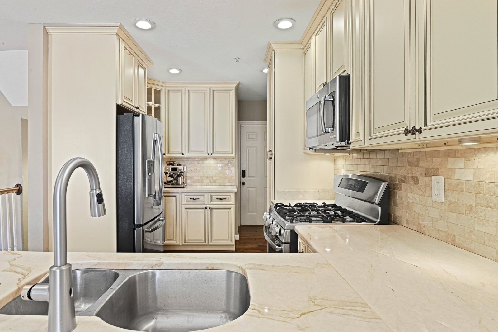 Kitchen sink and counters facing stainless refrigerator and gas range