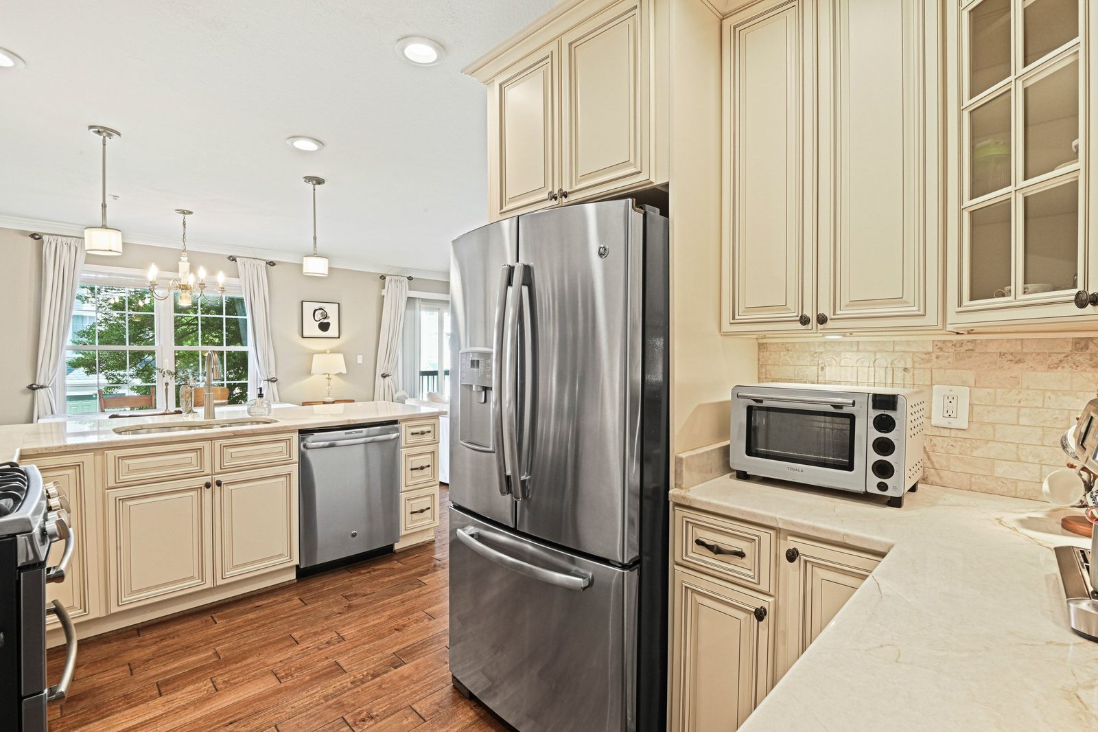 Stainless refrigerator and dishwasher in kitchen open to window-lit dining area