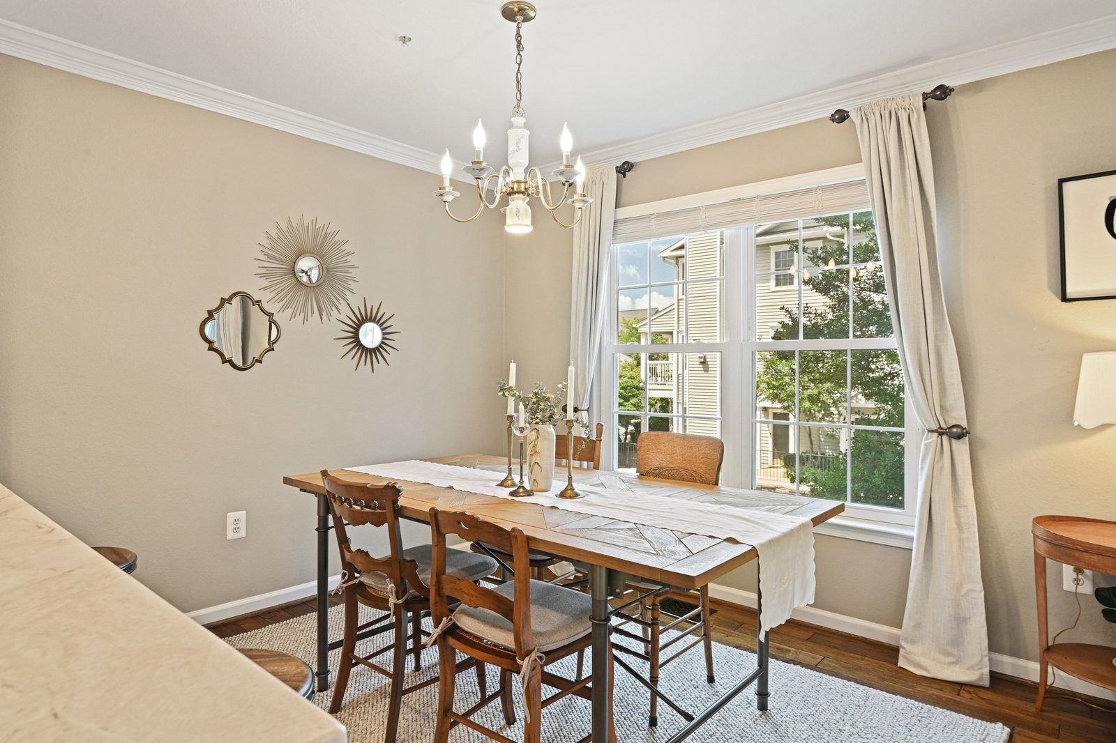 Dining area with chandelier, large window, hardwood floors, and crown molding