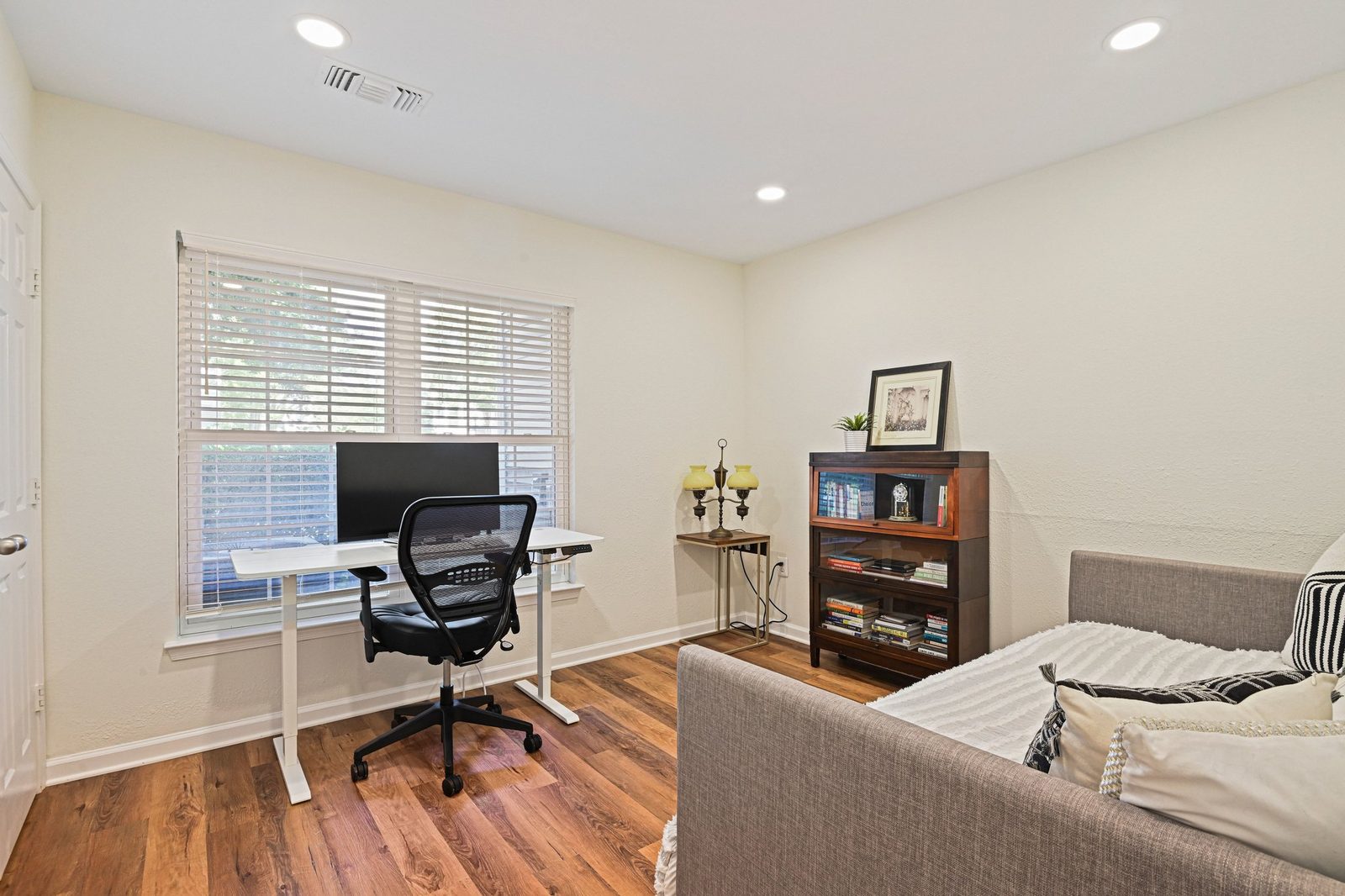 Second bedroom with wood-look plank floors, daybed, desk and bookcase