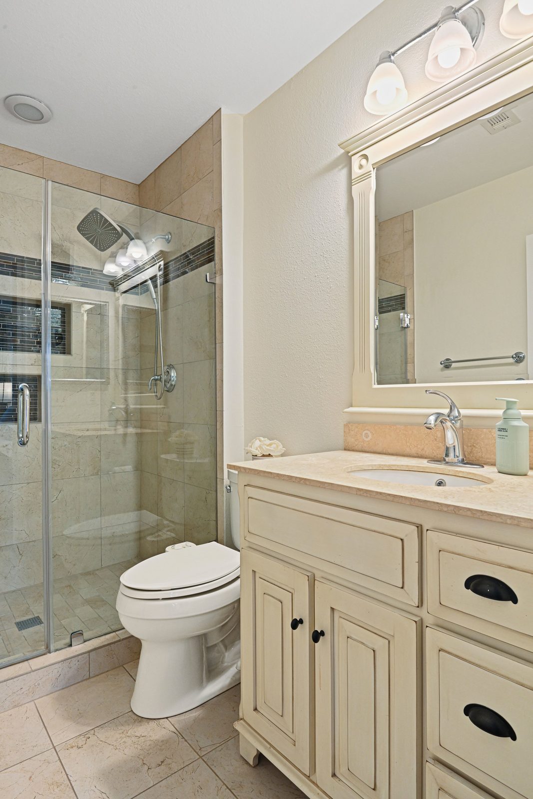 Full bath with glass shower, stone-look vanity top and framed mirror