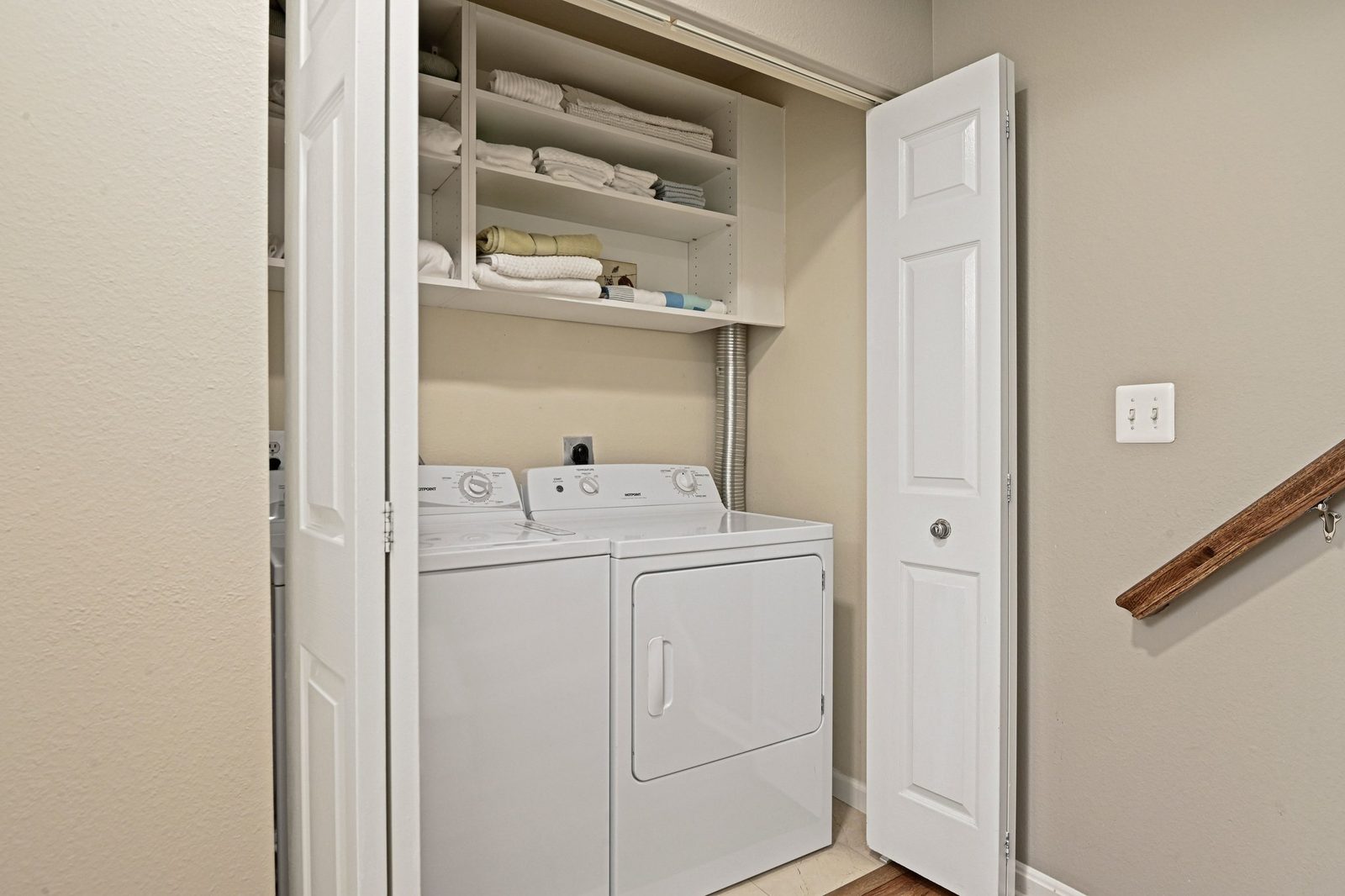 Laundry closet with side-by-side washer and dryer and shelving above