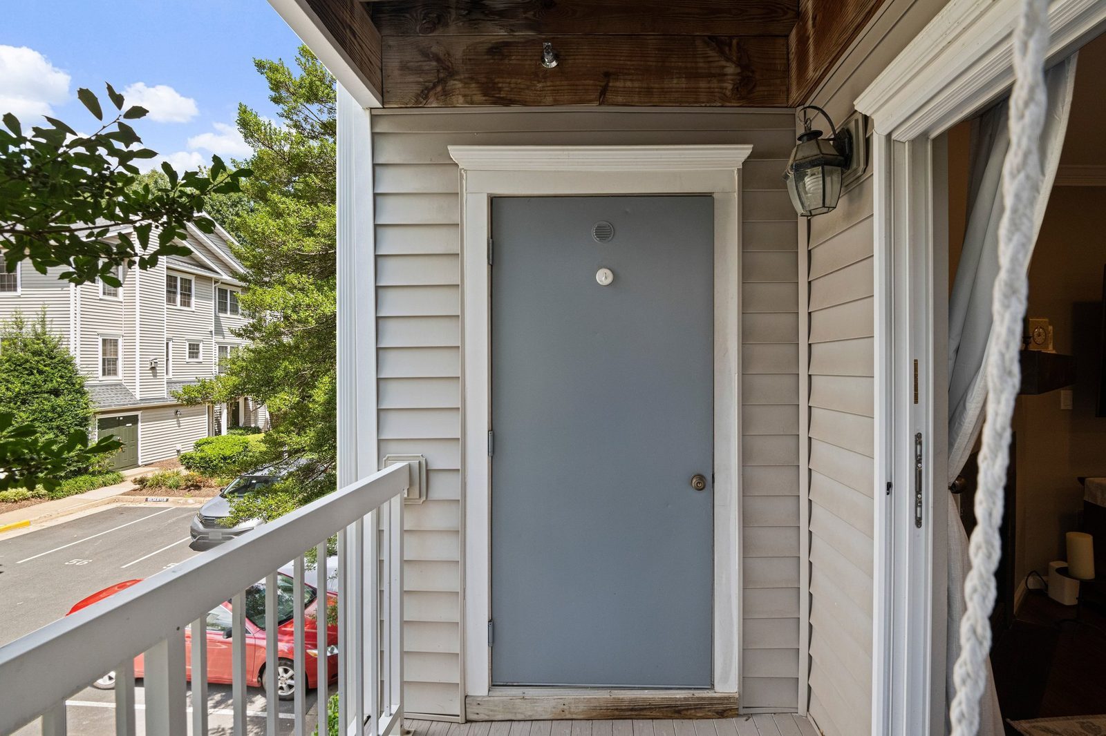 Covered entry landing with gray front door, coach light and sliding glass door