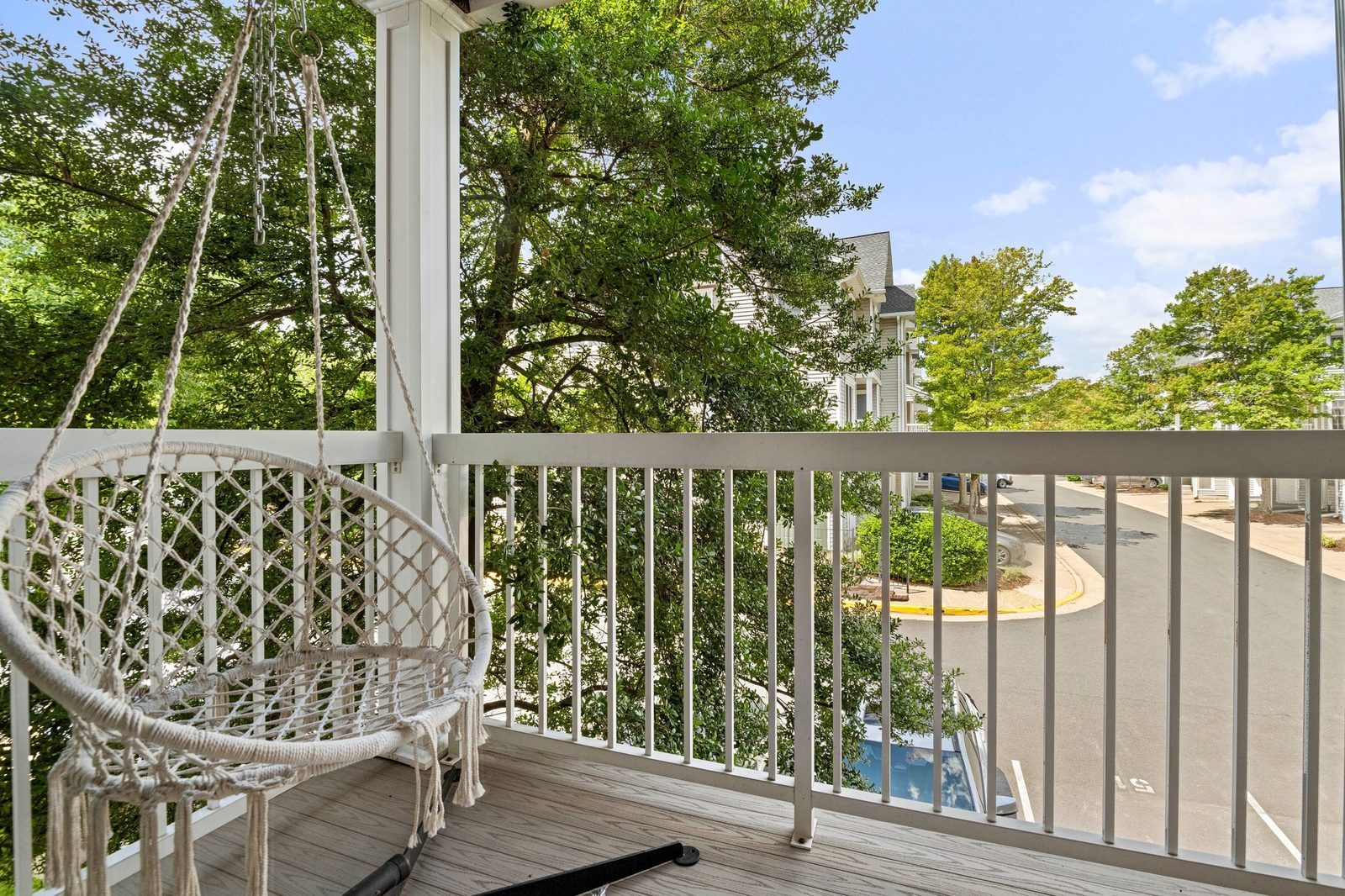 Balcony with rope swing chair overlooking mature trees and community drive