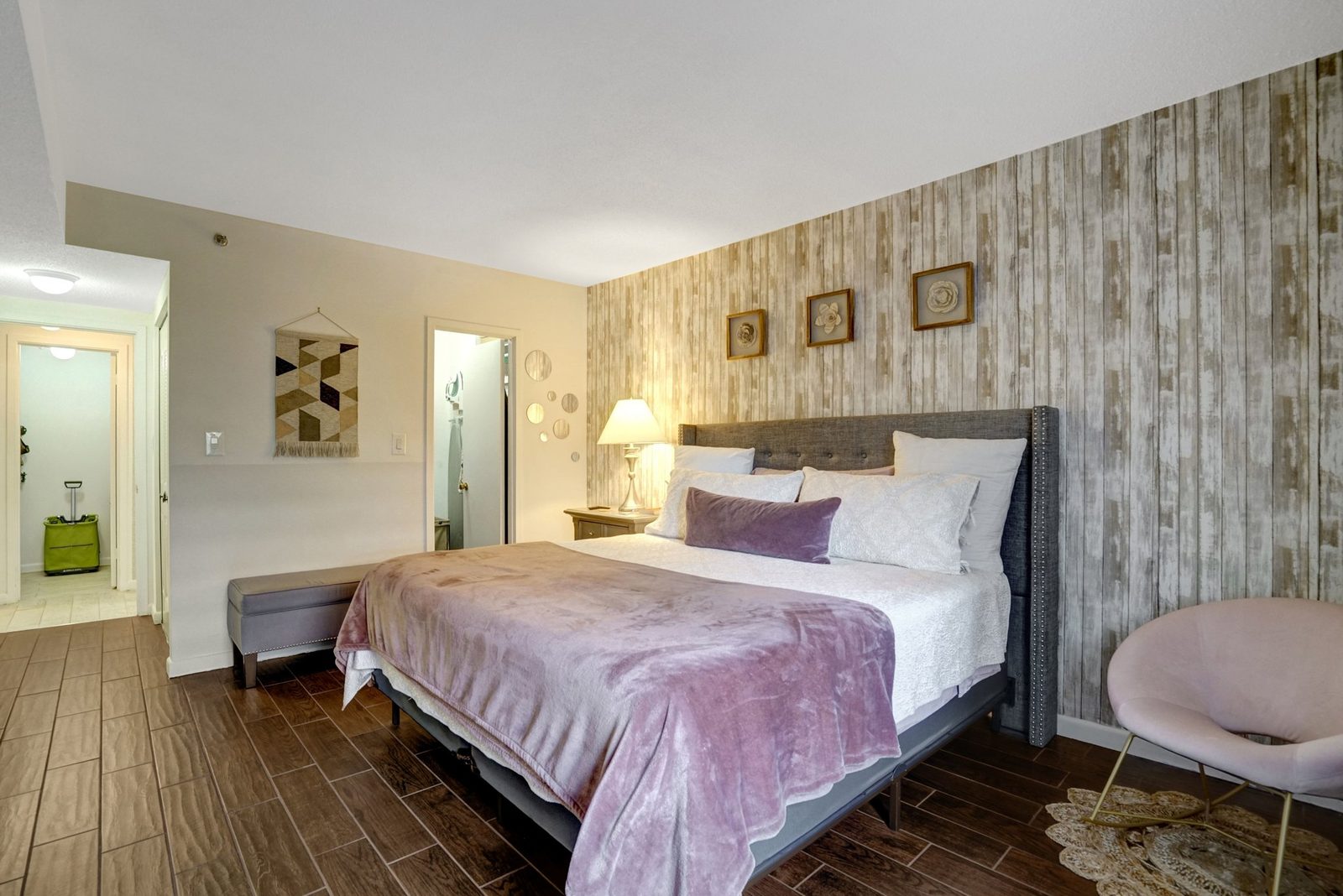 Bedroom with upholstered headboard, plank accent wall and bathroom doorway