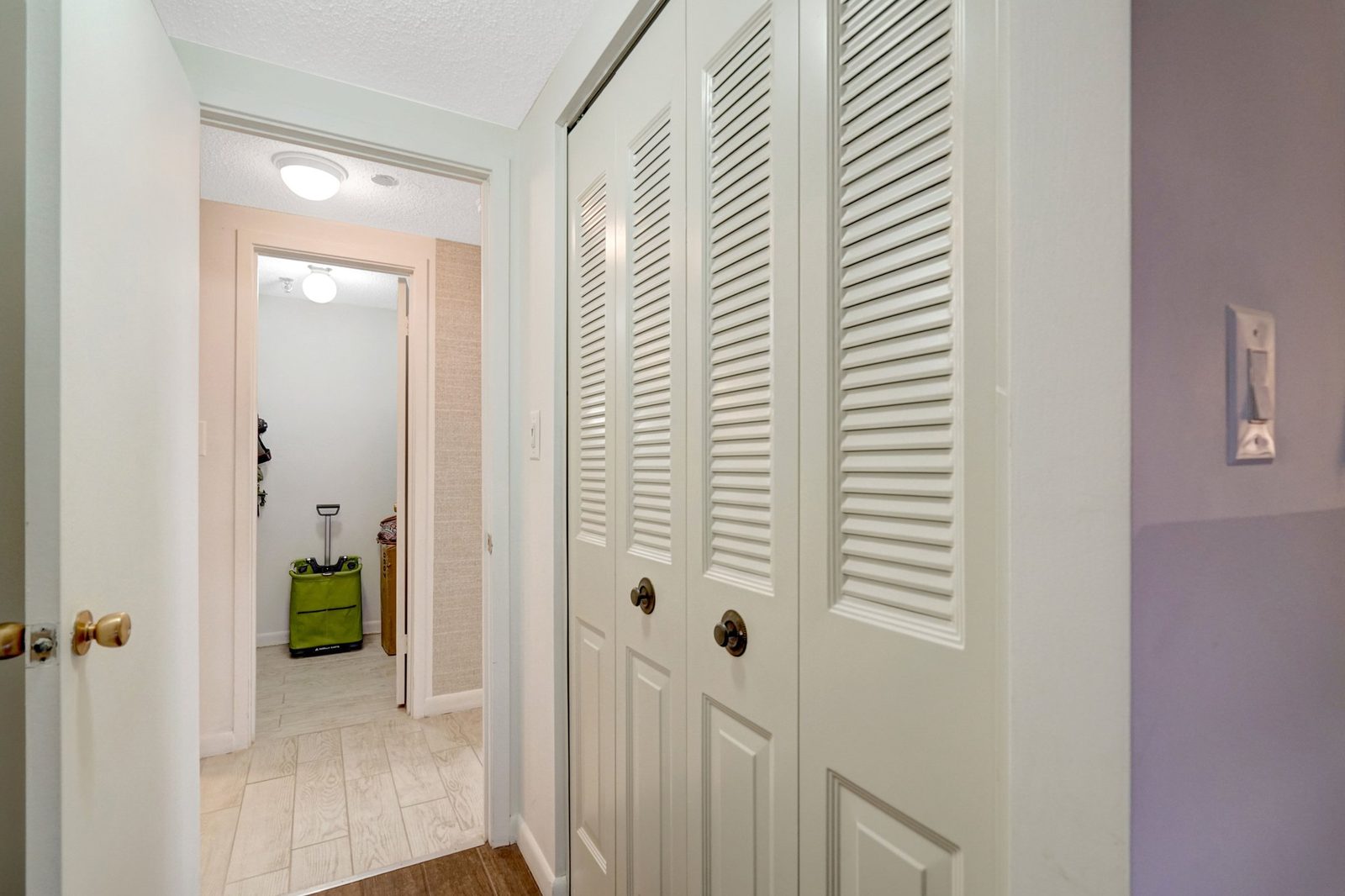Hallway with louvered bi-fold closet doors and light tile flooring