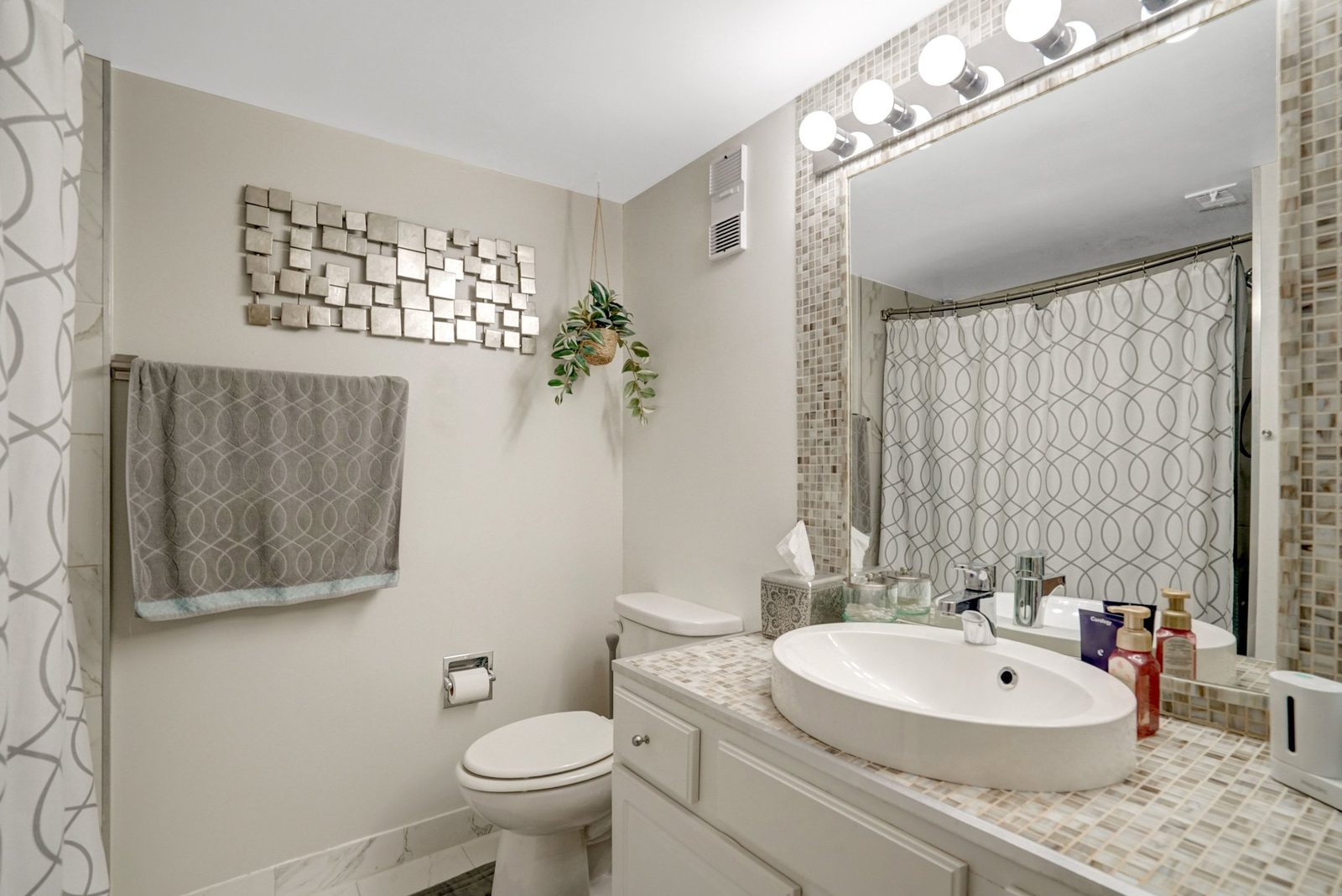 Bathroom with mosaic-tile vanity, oval sink and lighted mirror