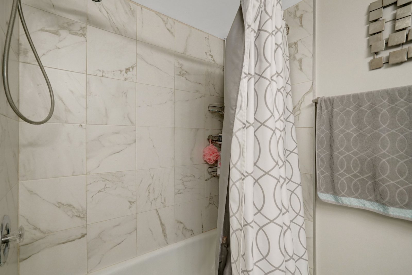 Bathtub with marble-look tile surround and handheld shower