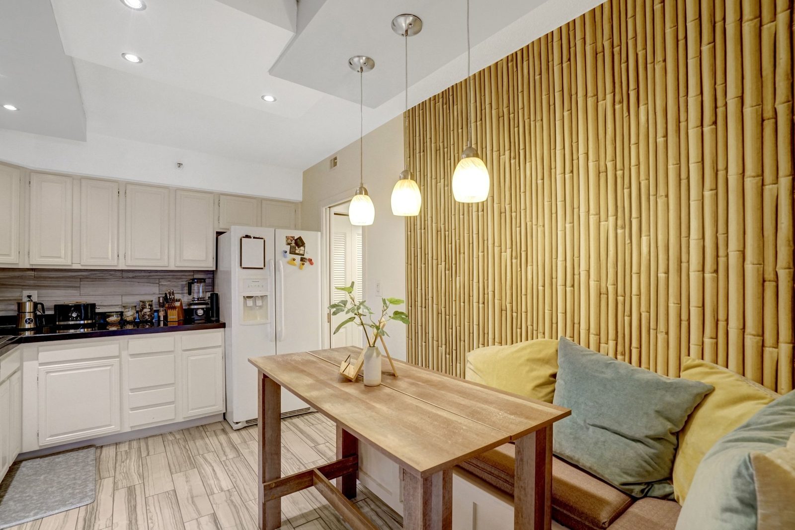 Dining table beside bamboo accent wall with view into kitchen