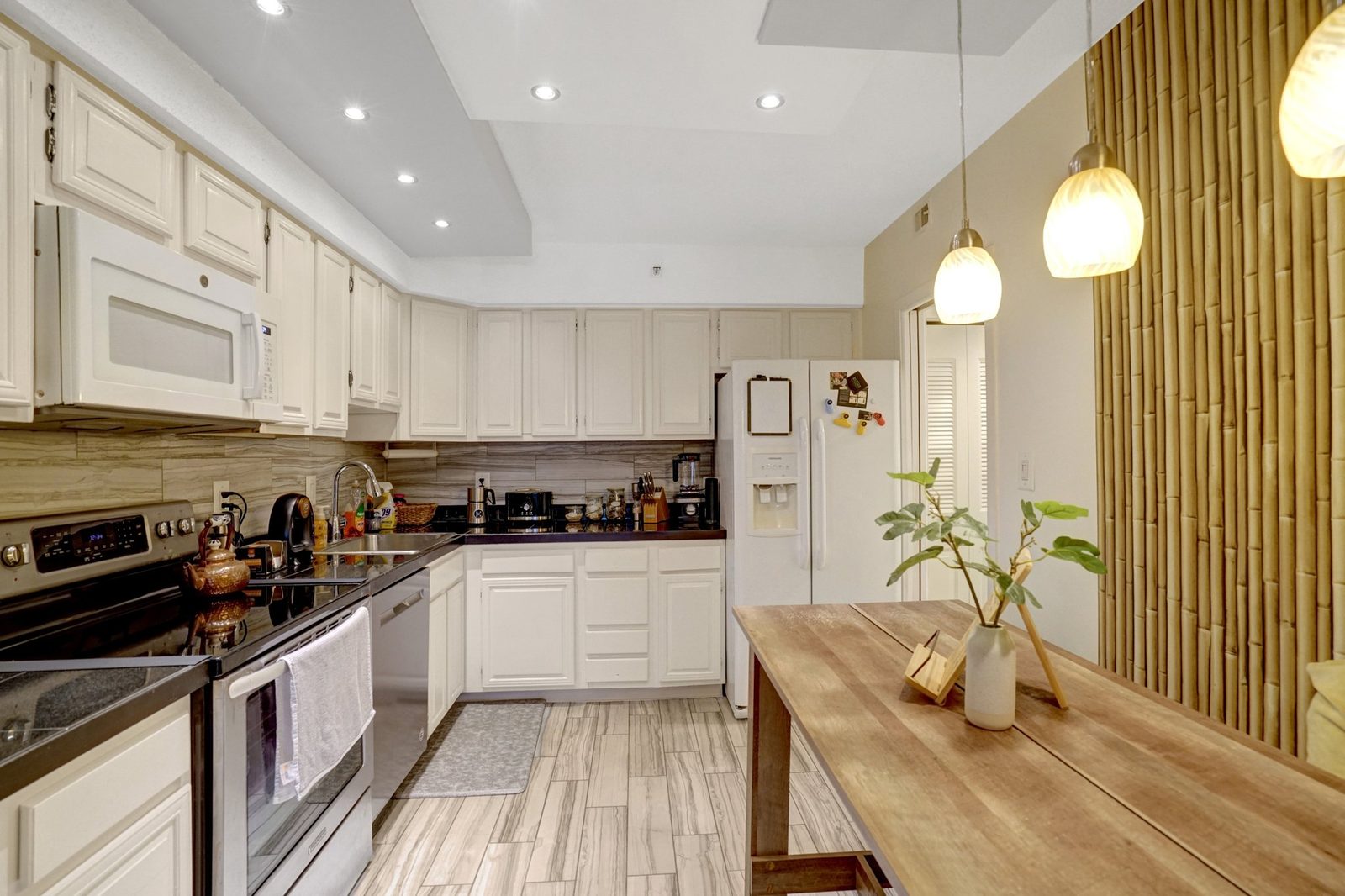 Galley kitchen with white cabinets, stainless range and tile flooring