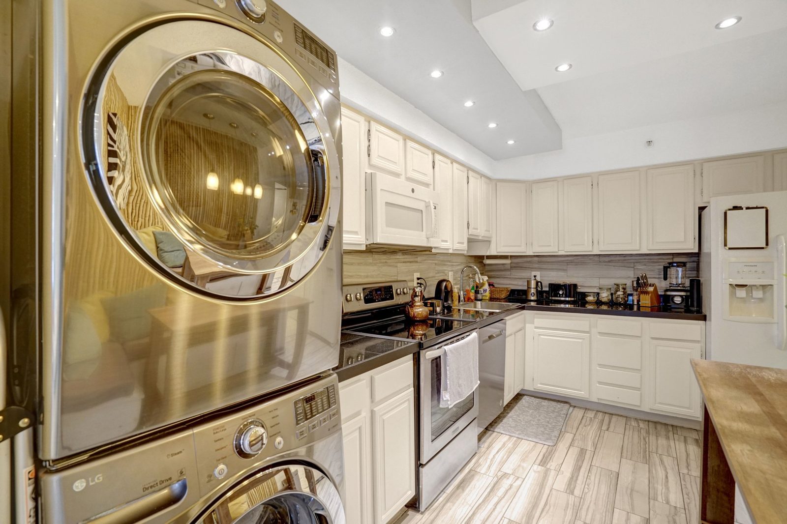 Kitchen with white cabinets, stainless range and stacked washer-dryer