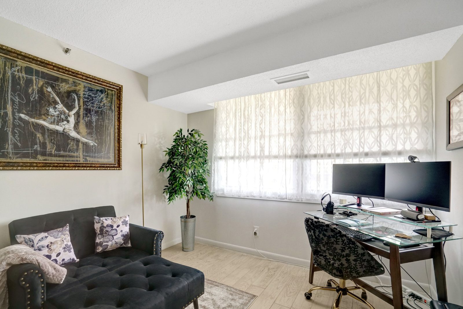 Bright room with sheer-curtained window, plank floor and seating area