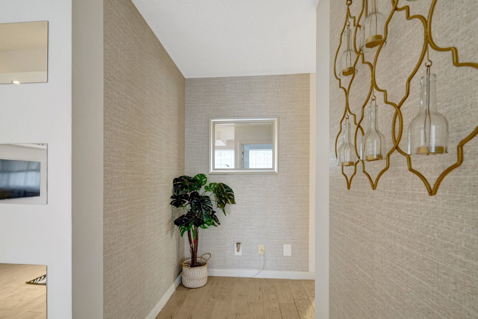 Hallway with textured wallpaper, wall mirror and light plank flooring