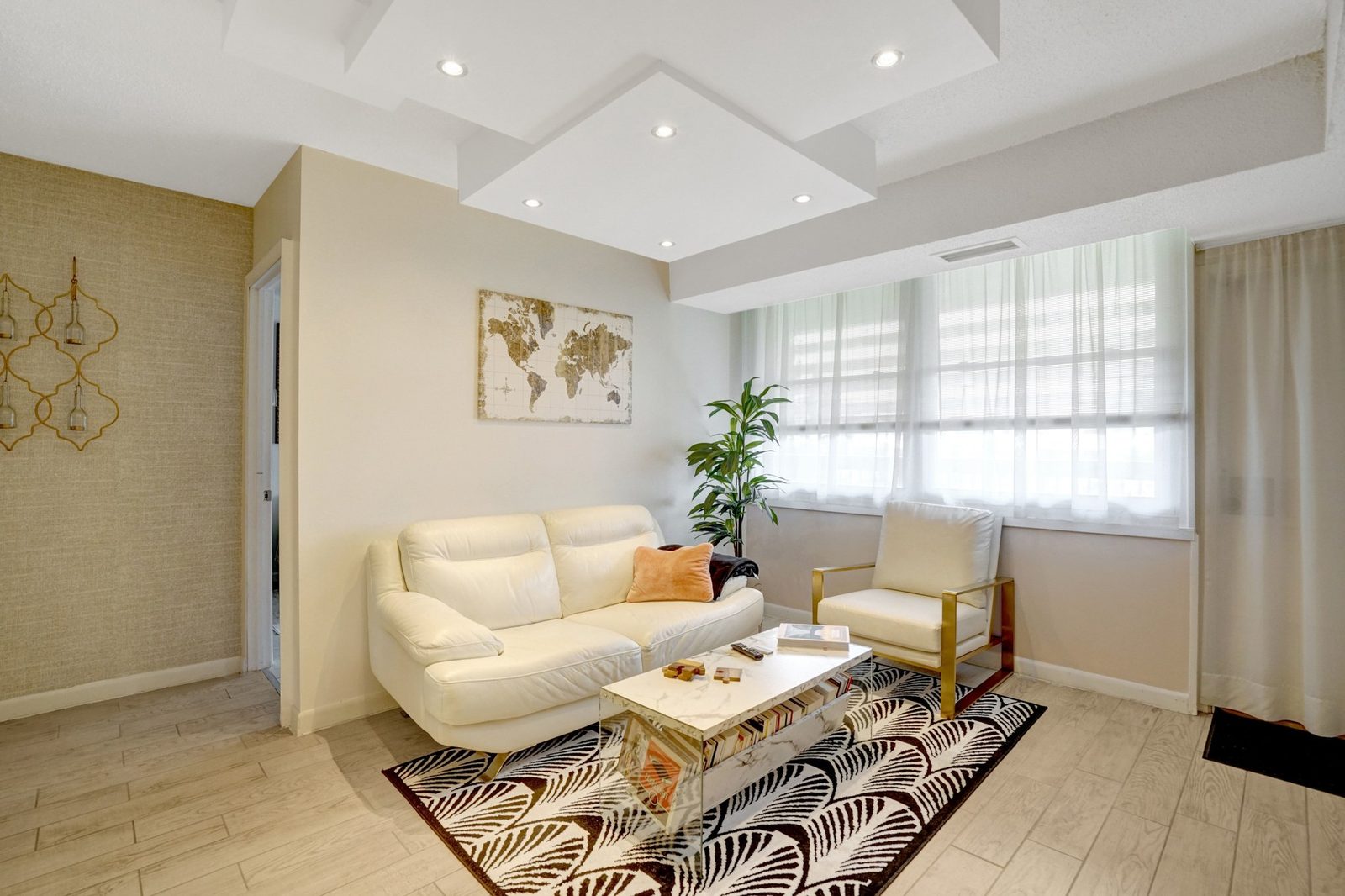 Living area with tray ceiling, window wall and light plank floors