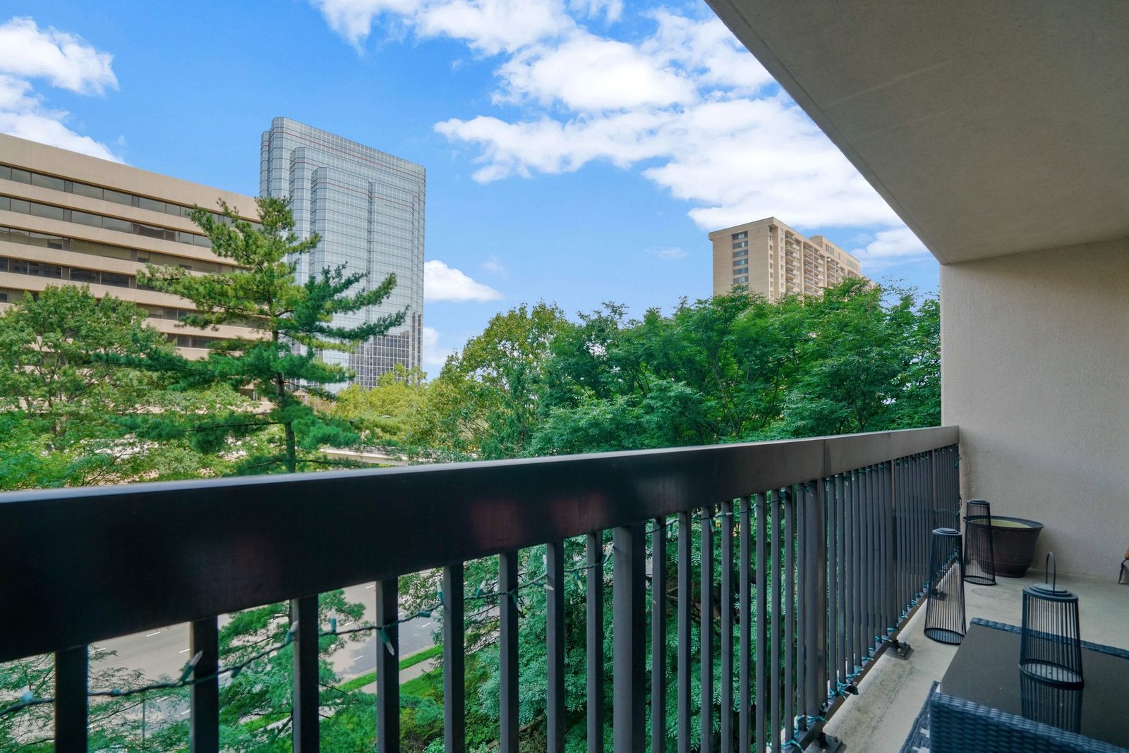 Balcony view of treetops, roadway and nearby high-rise buildings