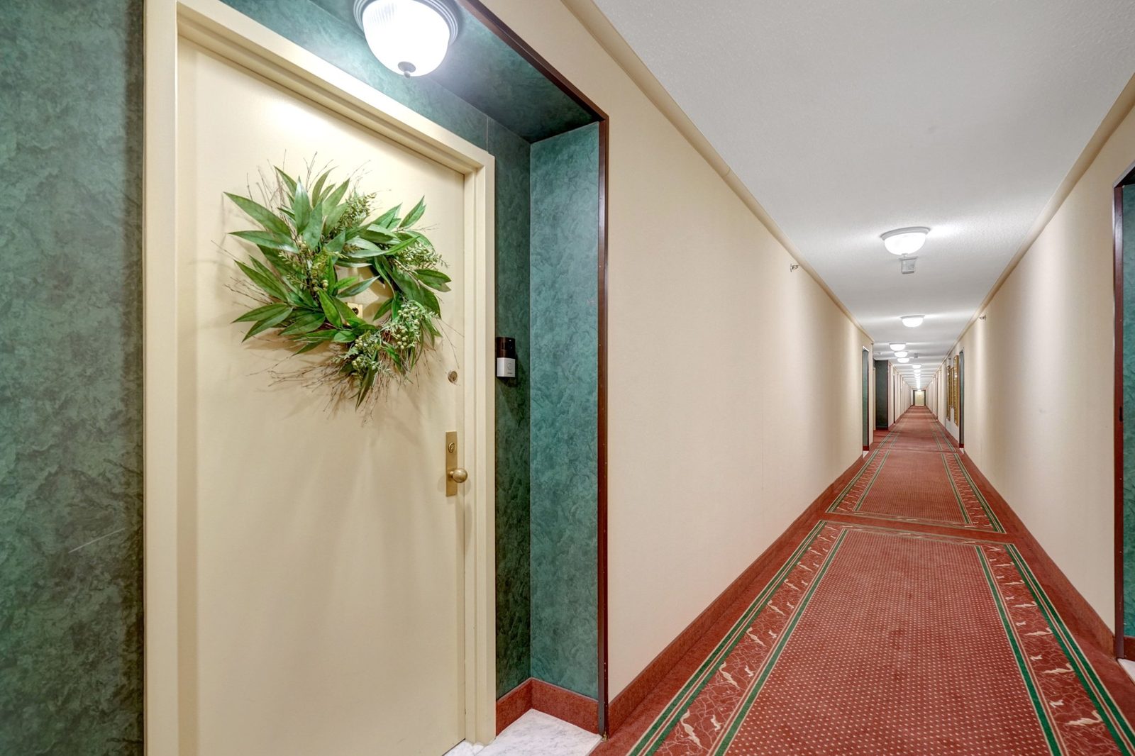 Building corridor with patterned carpet leading to unit entry door