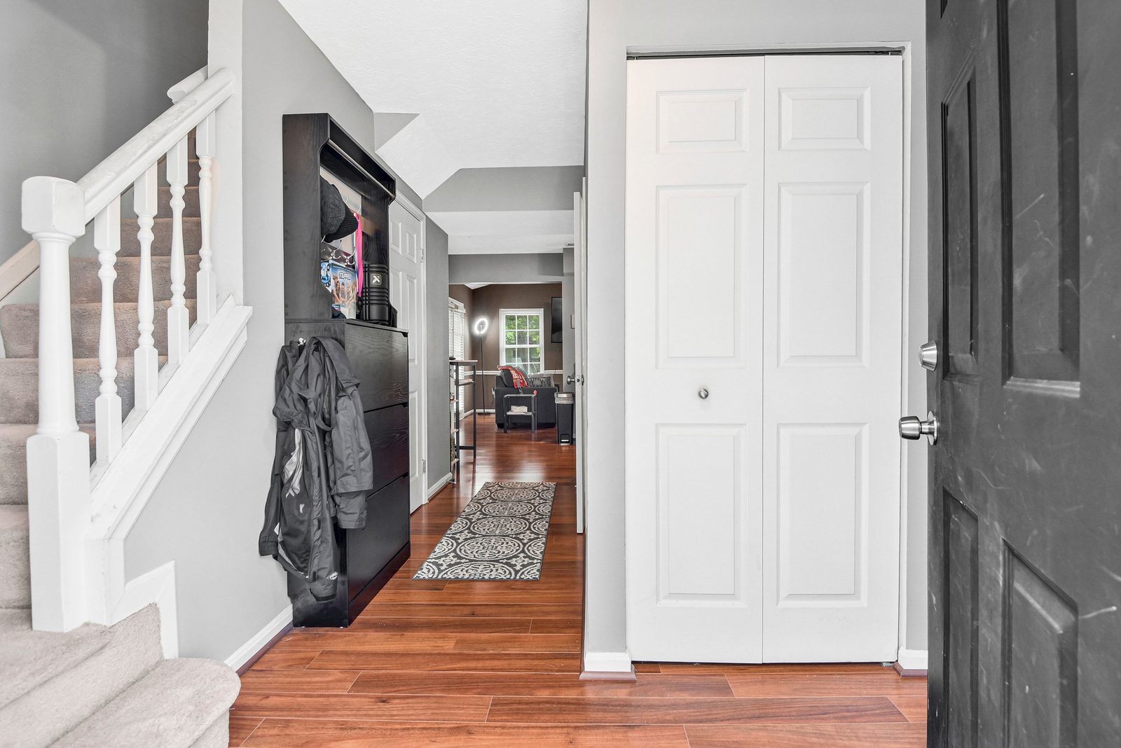 Entry hallway with wood-look floors, closet doors and carpeted staircase