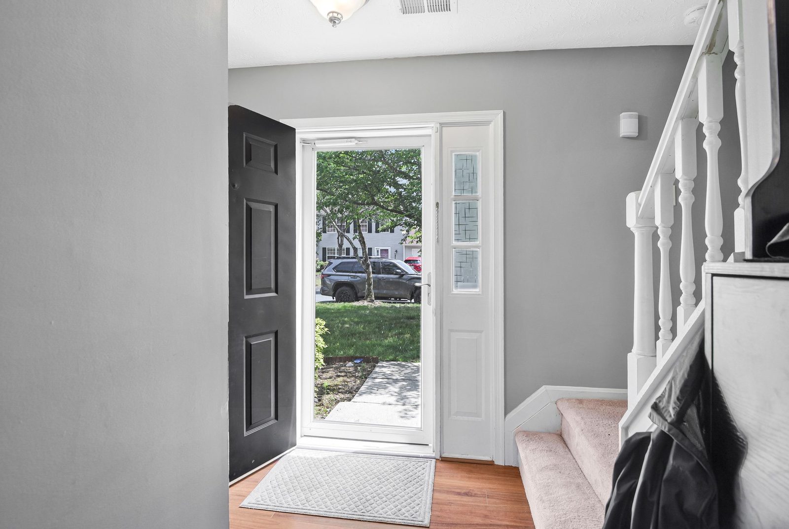 Foyer with open front door, sidelight window and carpeted stairs