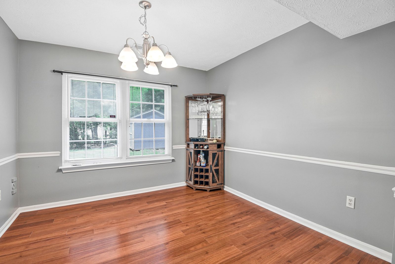 Dining room with wood-look floors, chandelier and corner bar cabinet