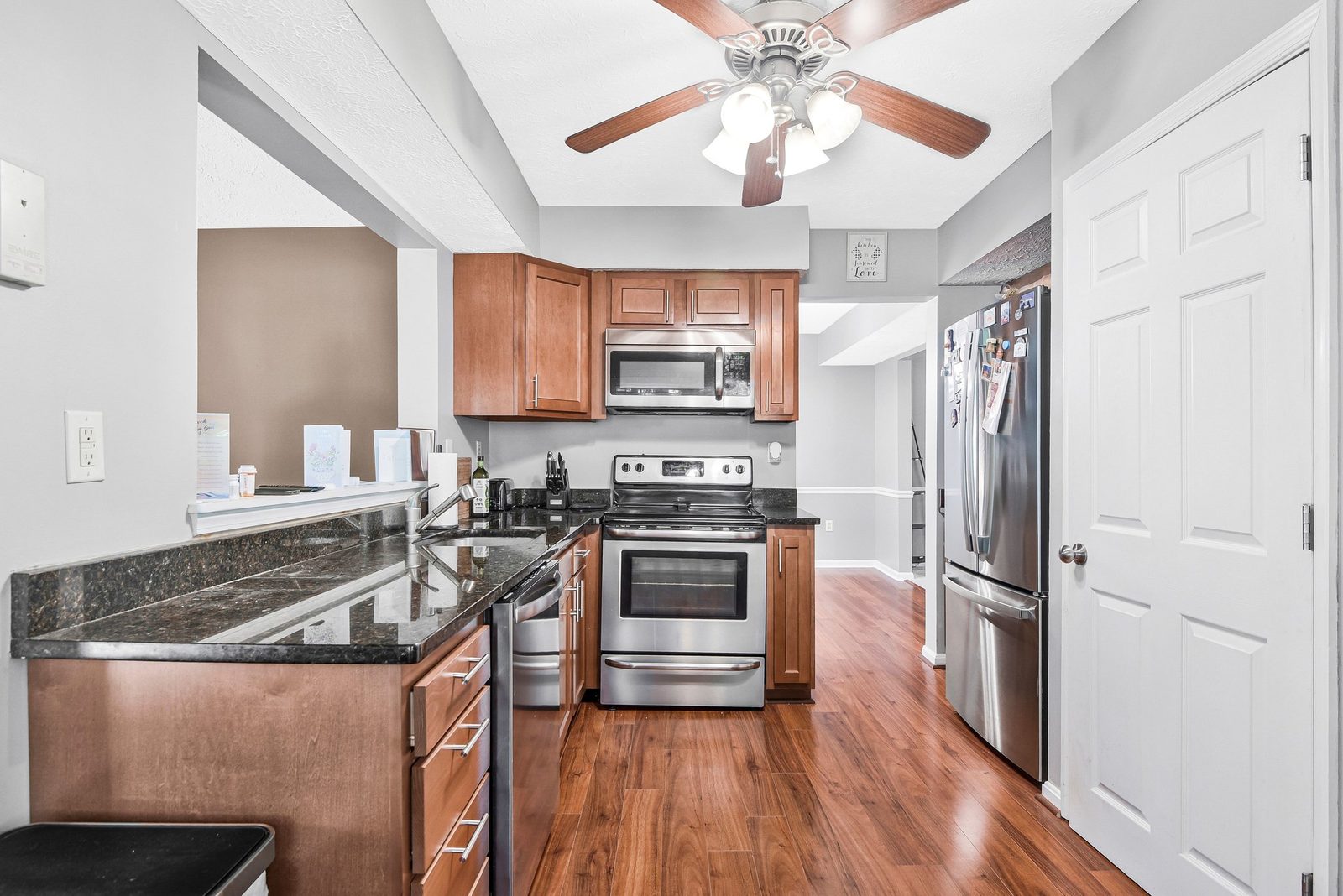 Kitchen with stainless appliances, dark stone counters and wood cabinets