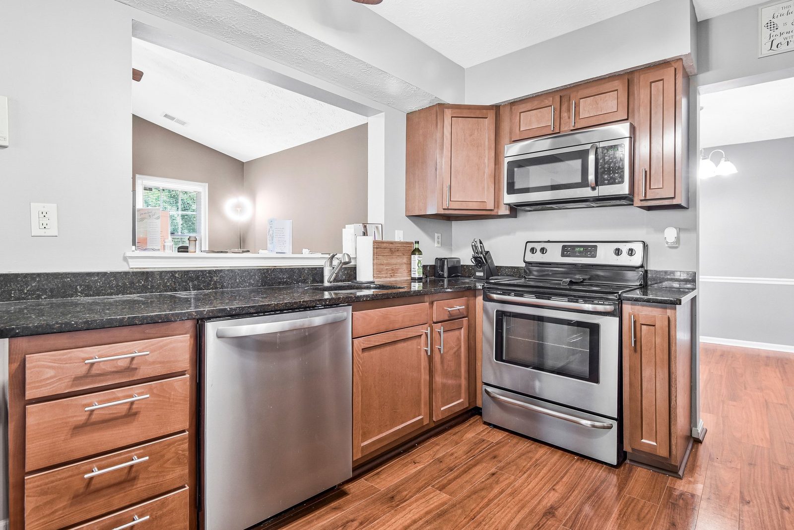 Kitchen with stainless dishwasher, range and pass-through to living area