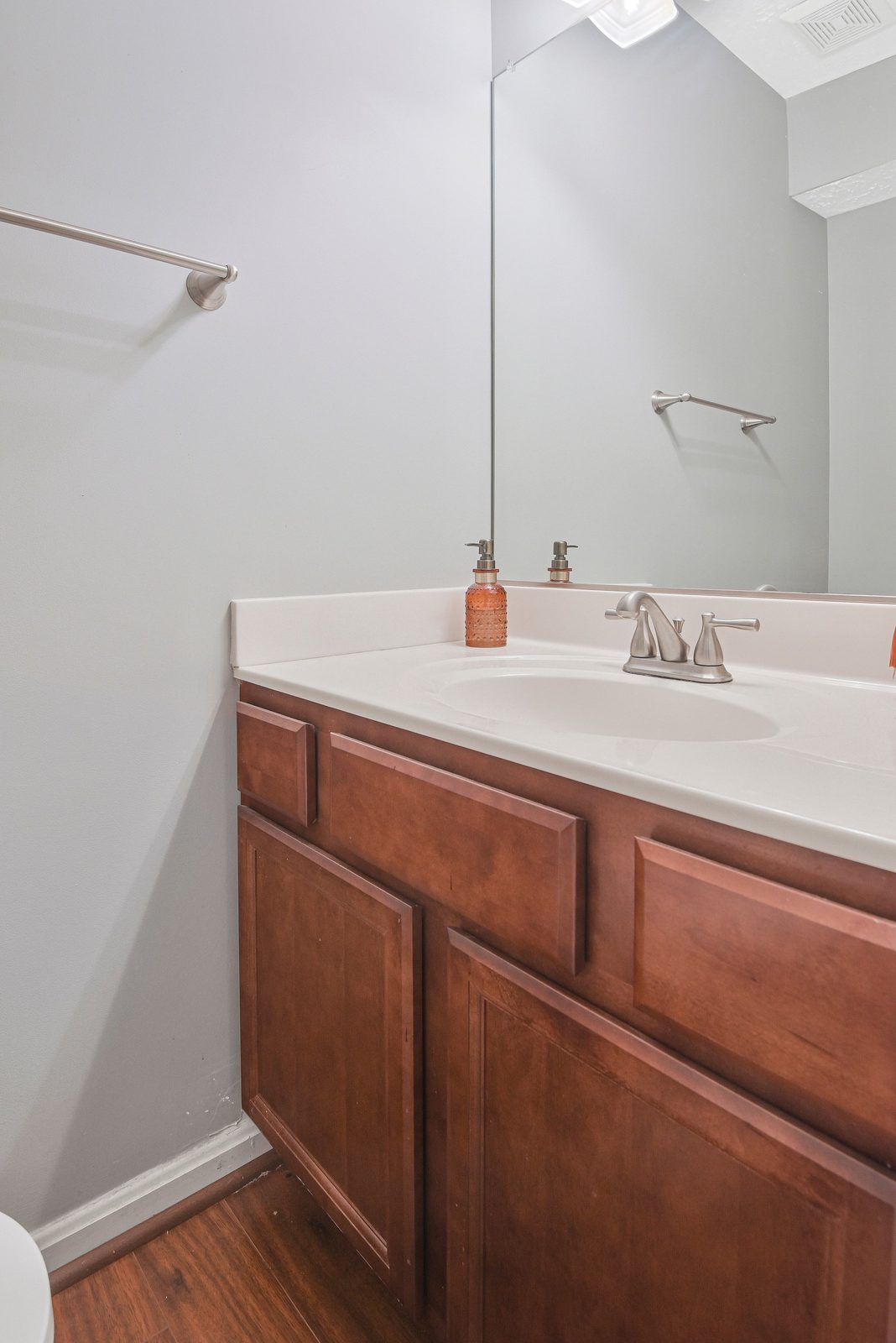 Wood vanity with white sink, brushed nickel faucet and wide mirror