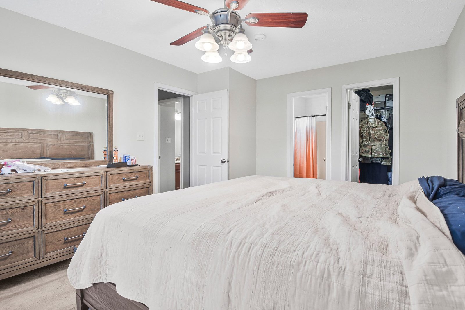 Carpeted bedroom with dresser, ceiling fan and walk-in closet