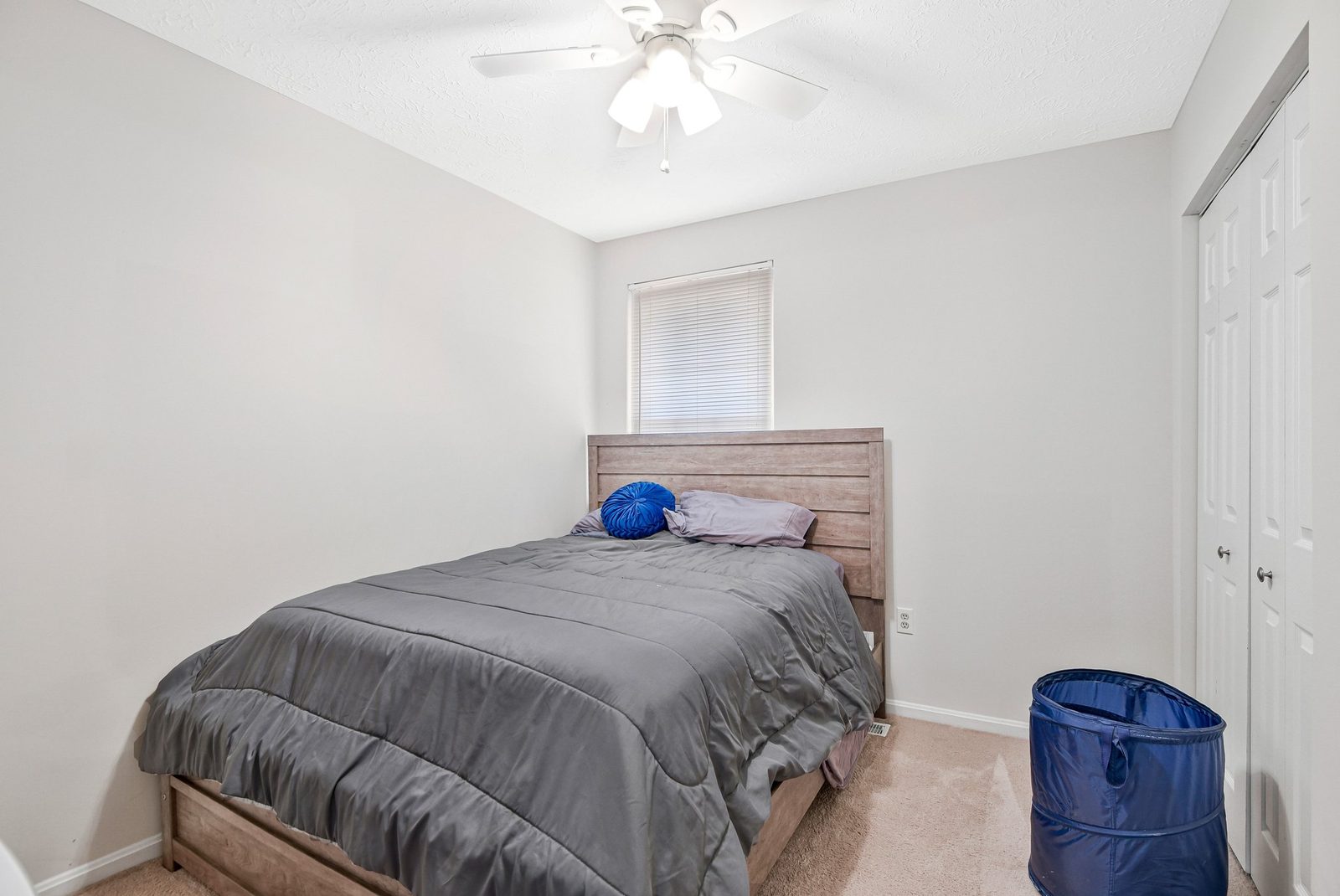 Carpeted bedroom with ceiling fan, window and double closet doors