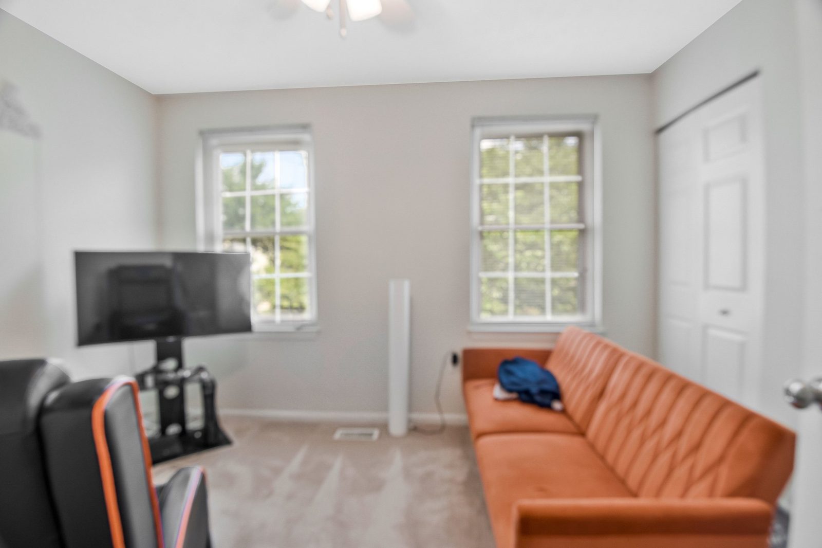 Carpeted room with two windows, closet door and wall-mounted TV