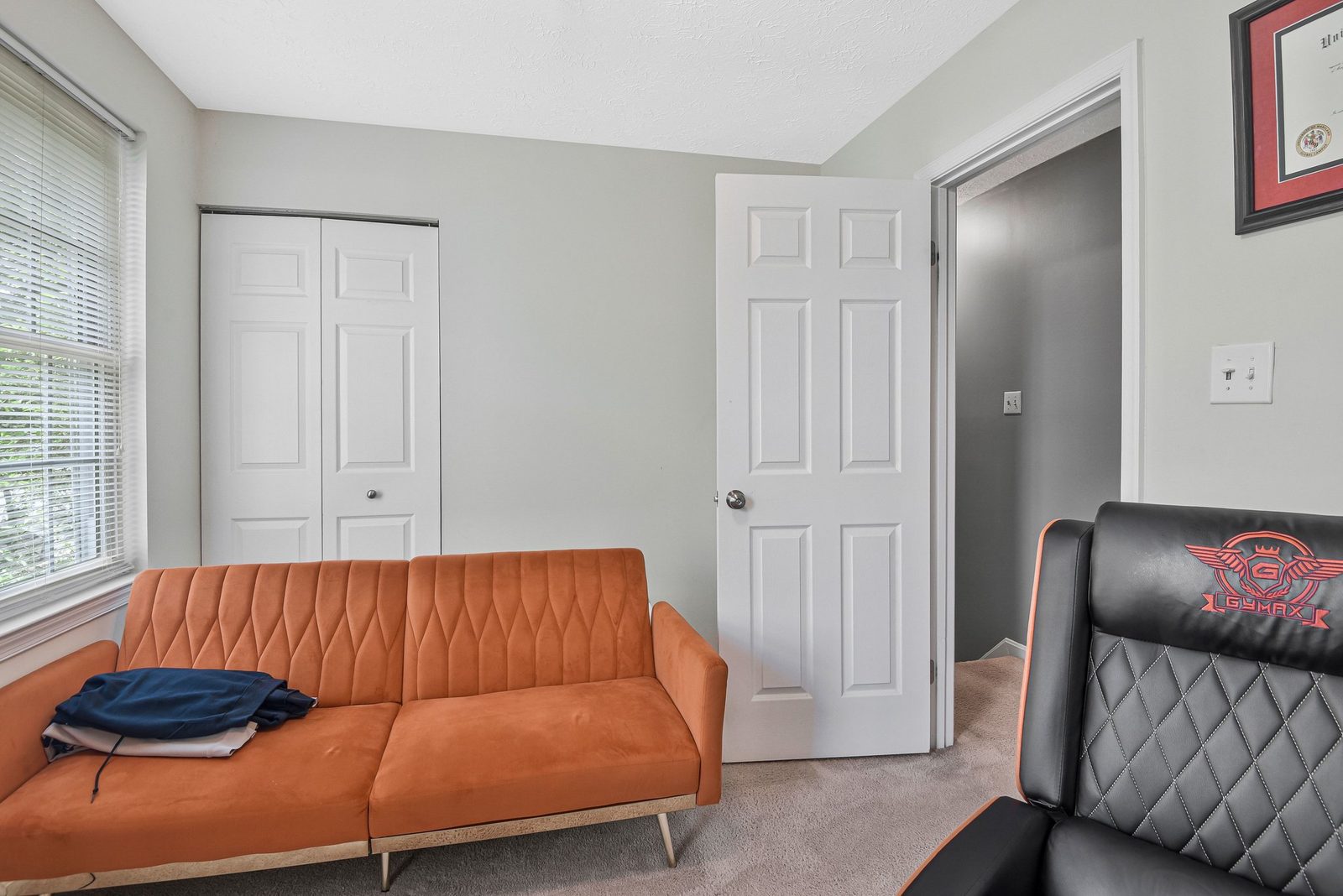 Carpeted room with double closet doors, window and hallway doorway