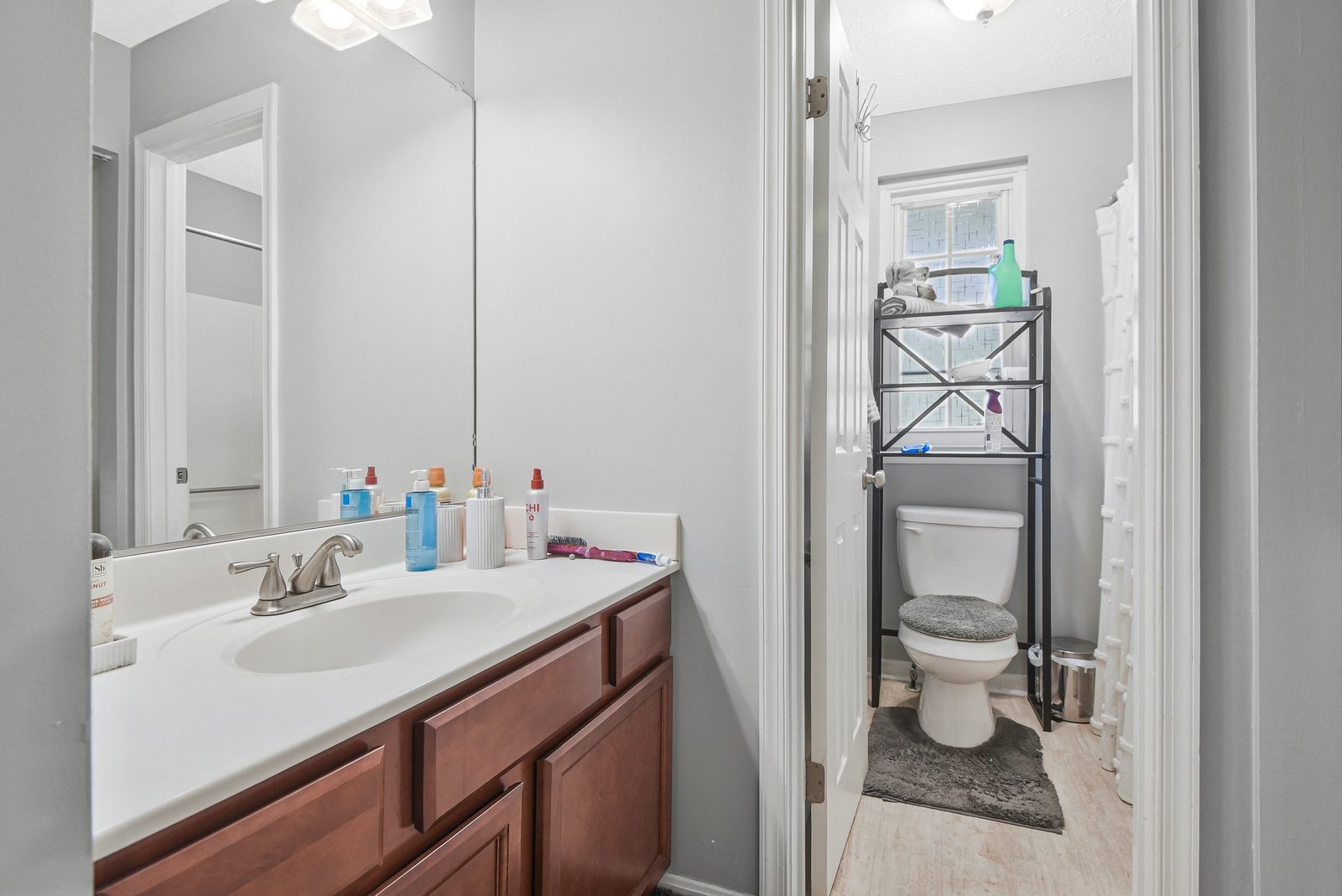 Bathroom vanity with white counter, wood cabinets and large mirror