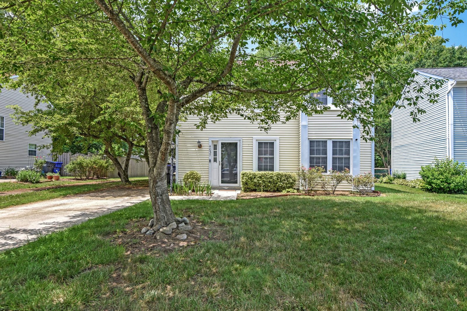 Front exterior with light siding, shade tree and front lawn