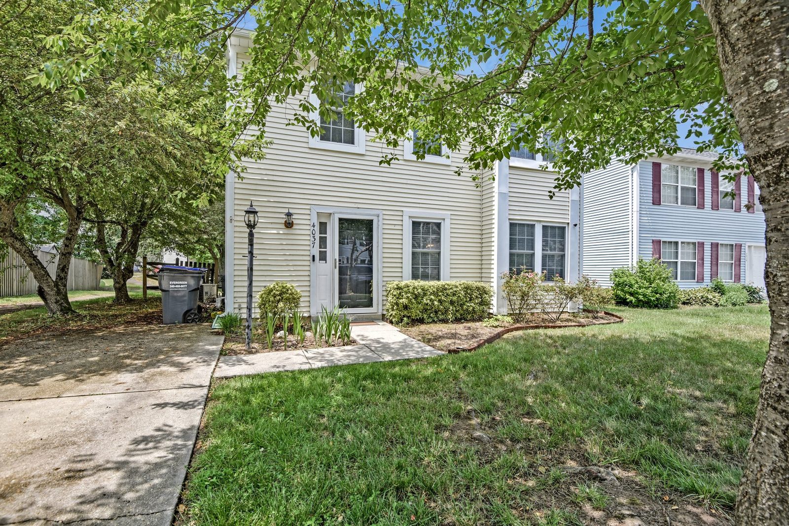 Front entry with storm door, lamp post and foundation shrubs