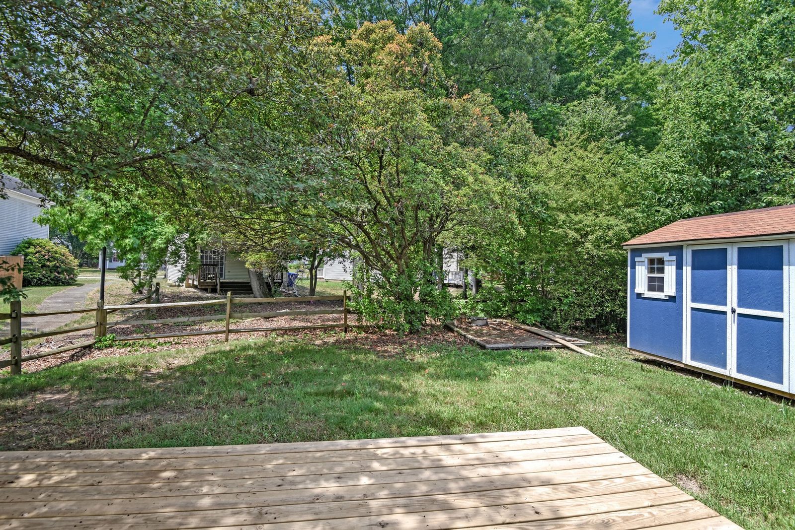 Backyard with wood deck, split-rail fence and blue storage shed