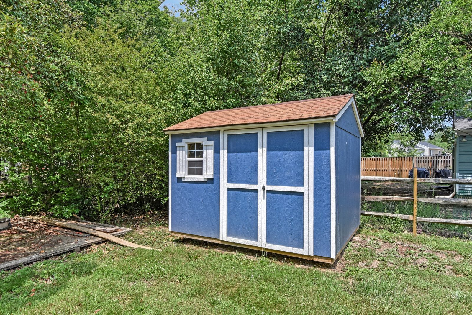 Blue storage shed with shingled roof and double doors
