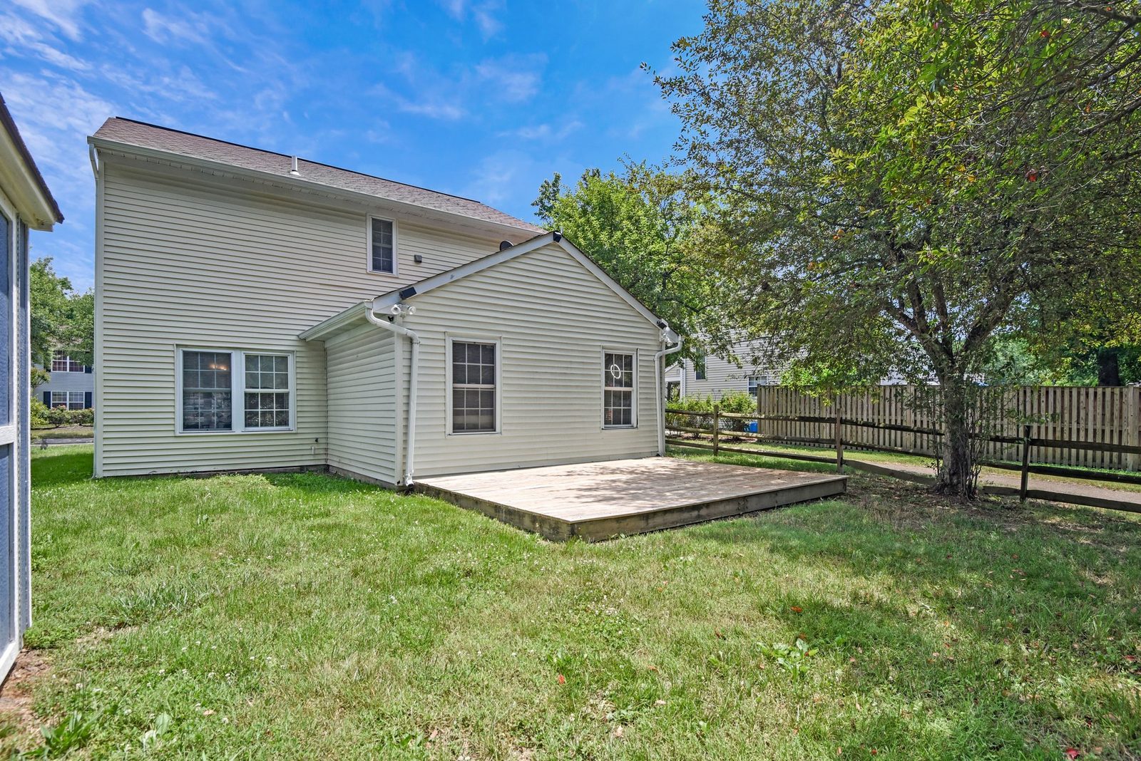 Rear exterior with wood deck and grassy fenced yard