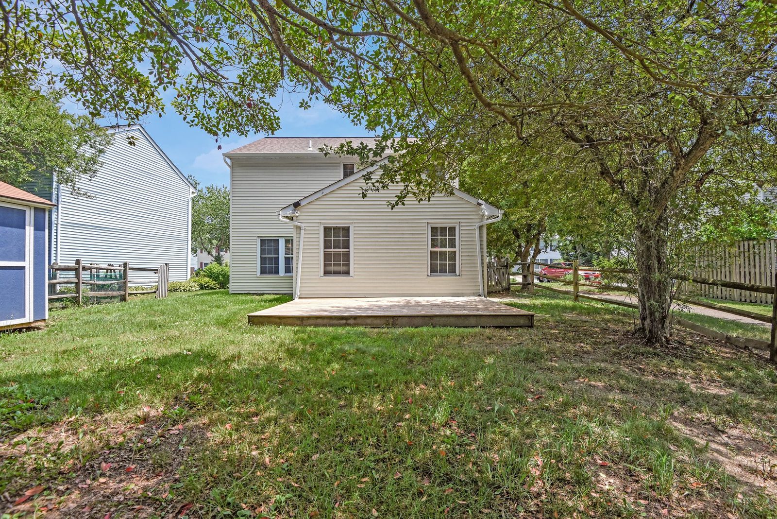 Rear of home with deck, lawn and split-rail fence