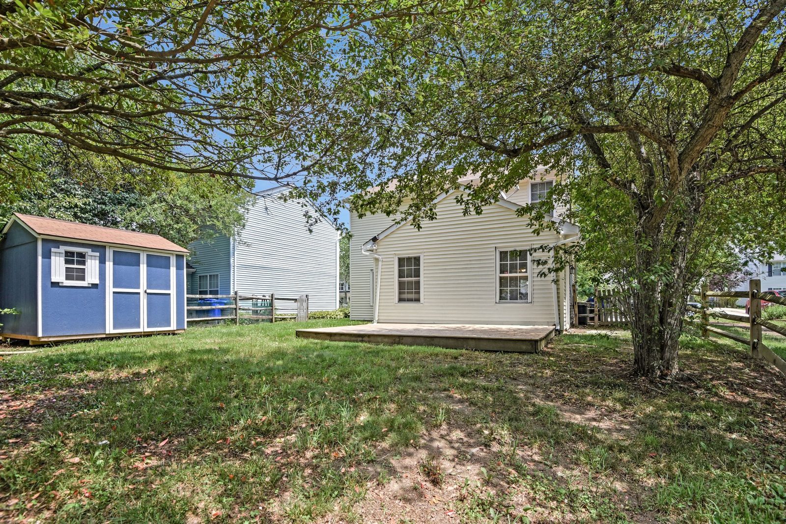 Backyard with shade tree, storage shed and wood deck