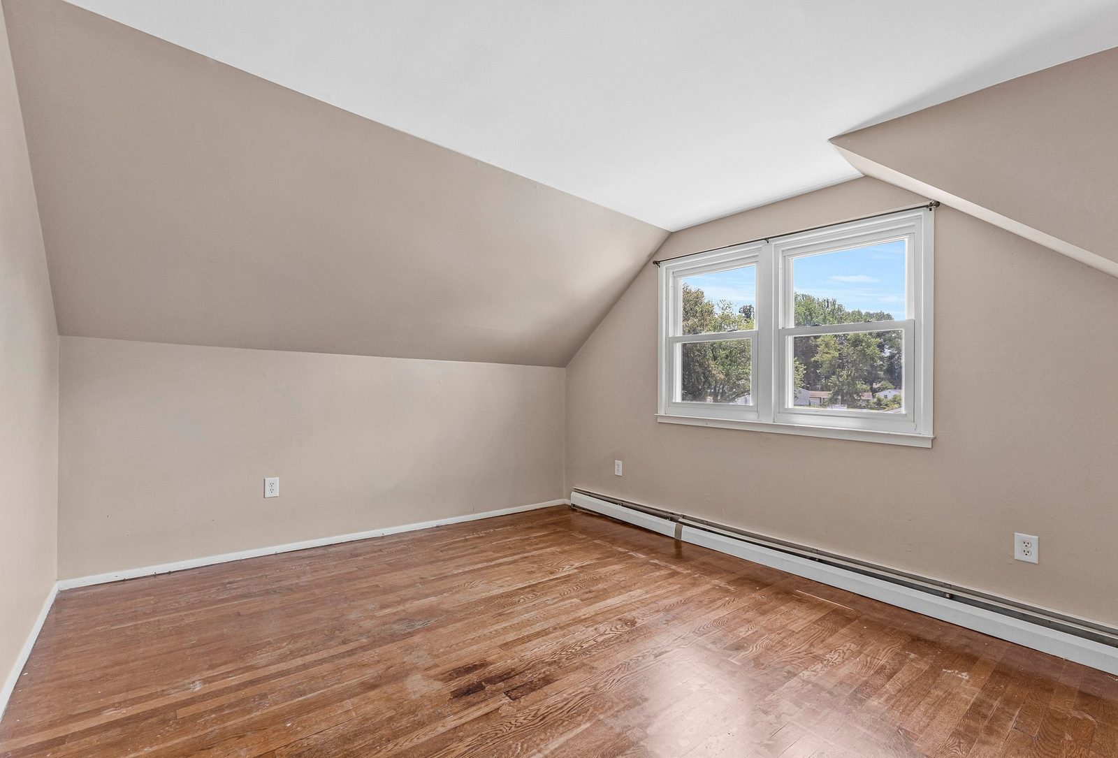 Upper-level room with sloped ceiling, hardwood floors and double window