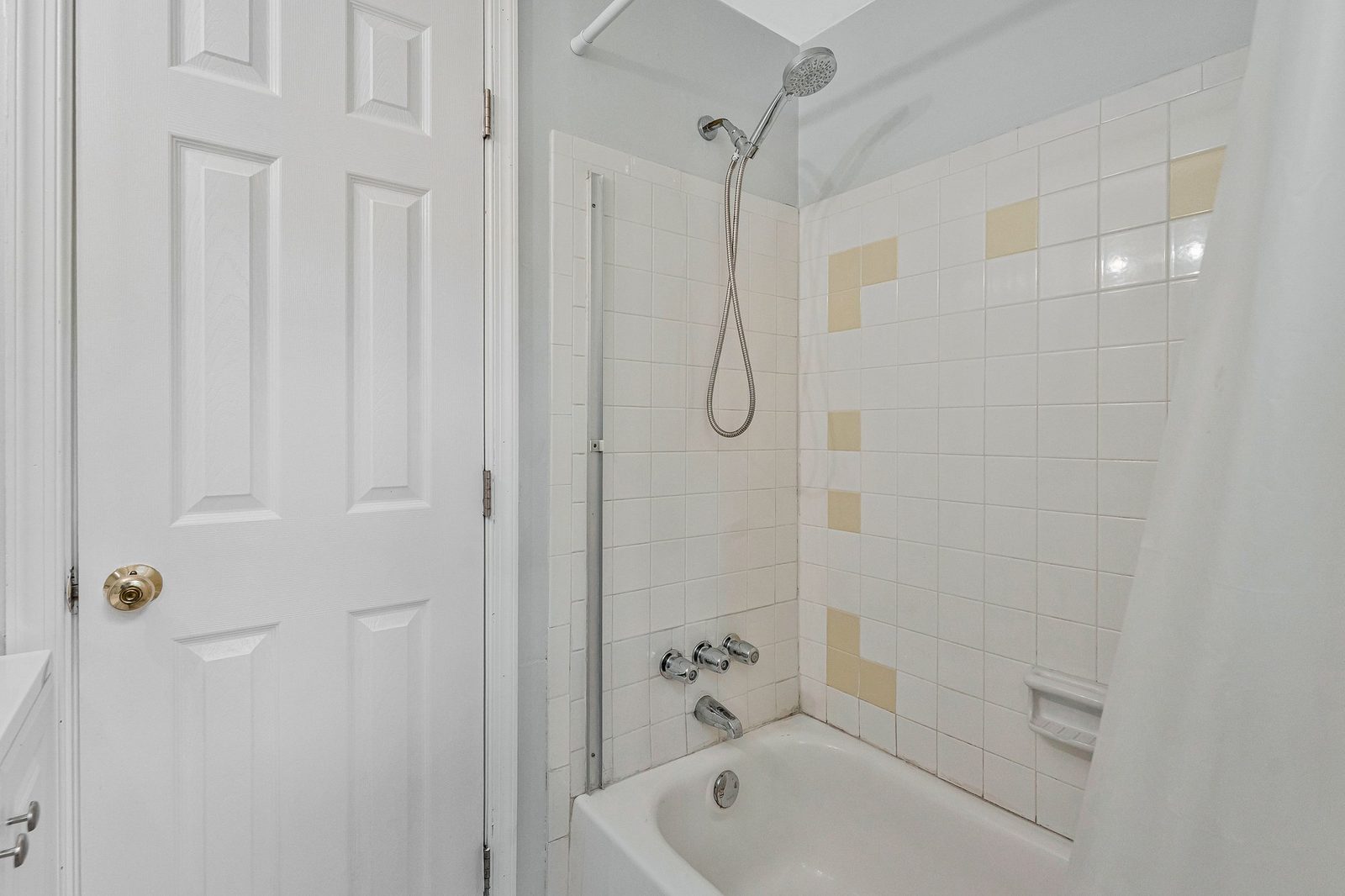Tub and shower with white and beige tile surround