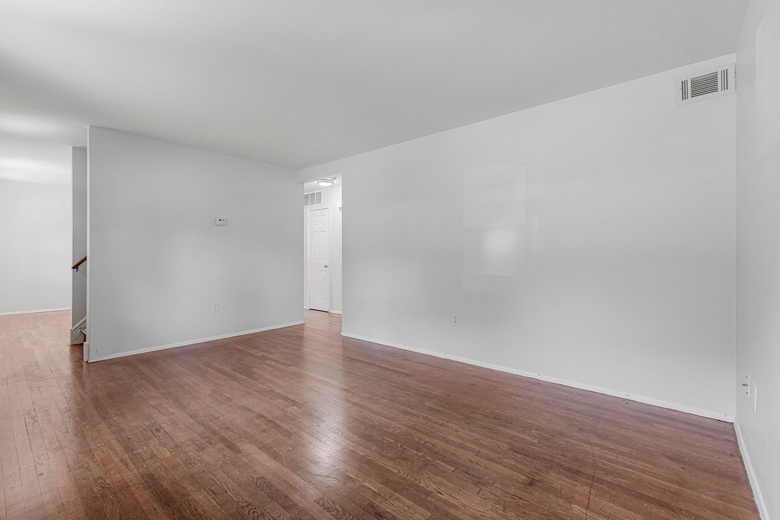 Open living area with hardwood floors and stairway railing at left
